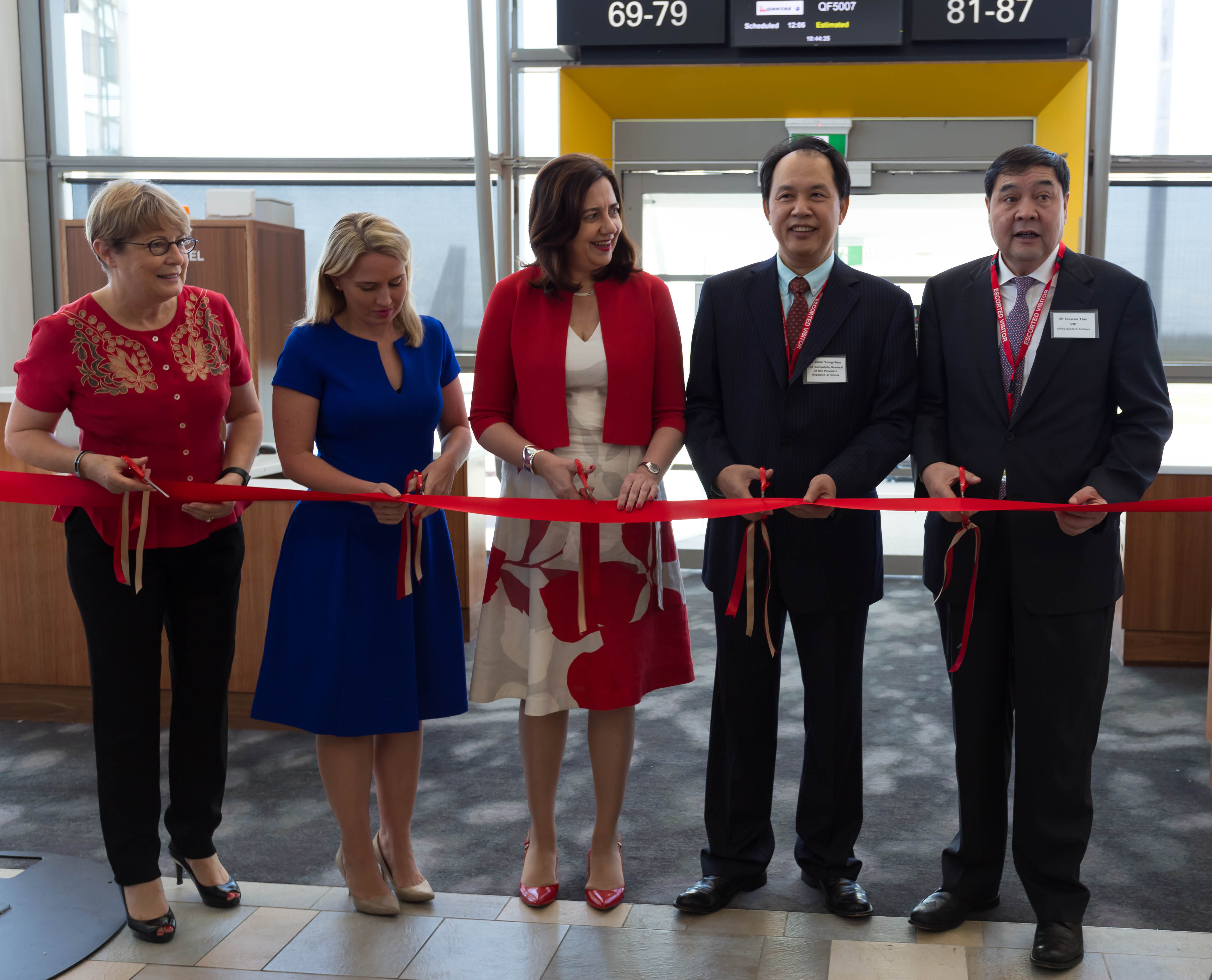 a group of people cutting a red ribbon