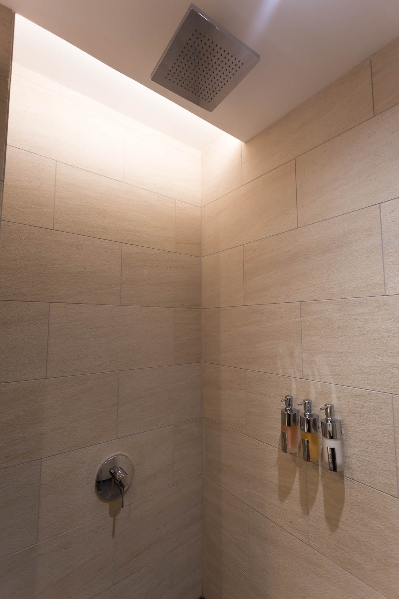 a shower with soap dispensers and a light above it