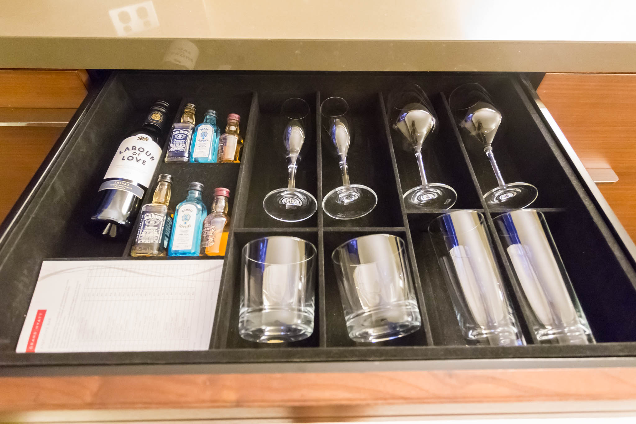 a drawer with wine glasses and bottles