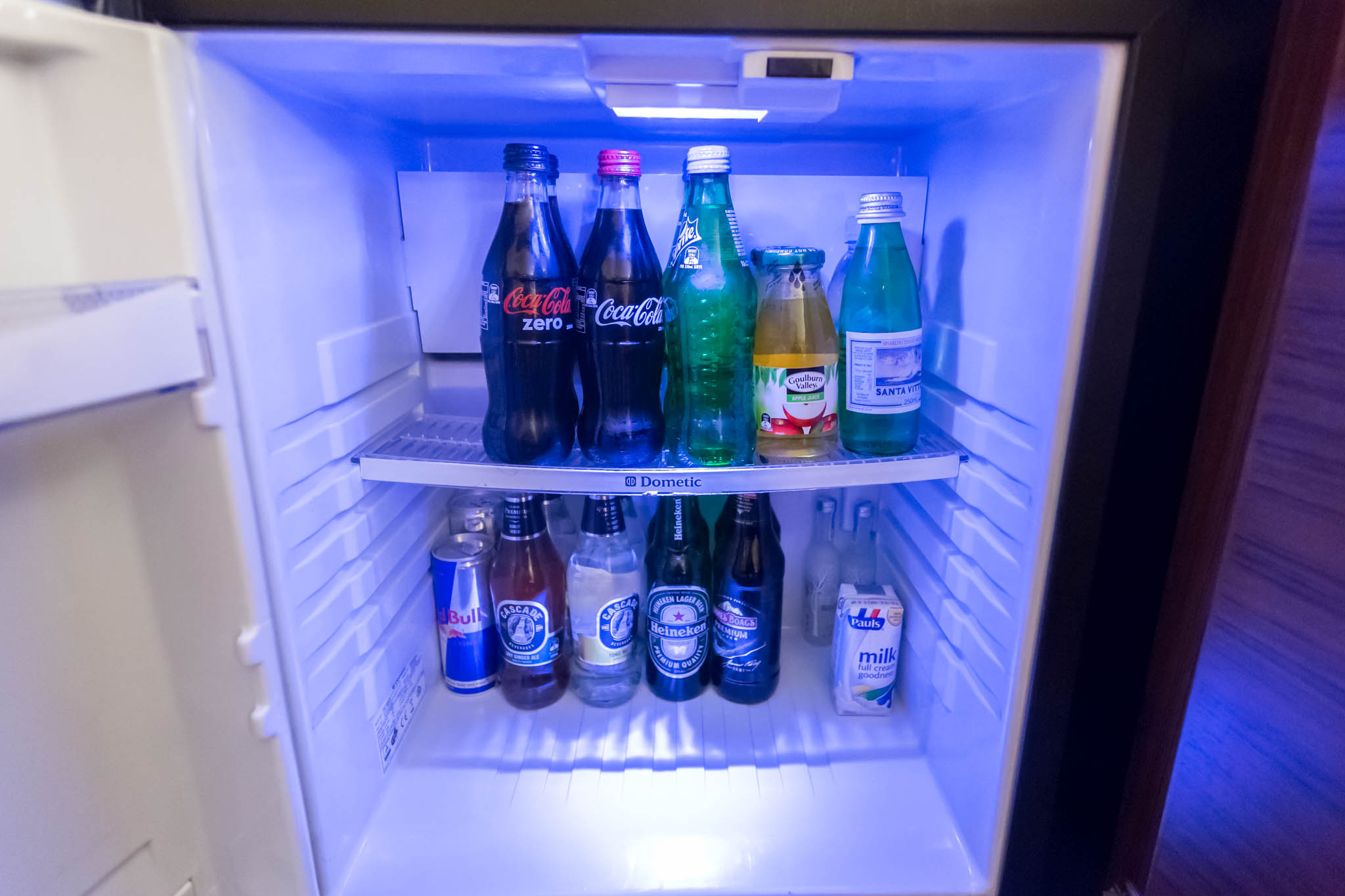 a refrigerator with bottles of soda and other beverages