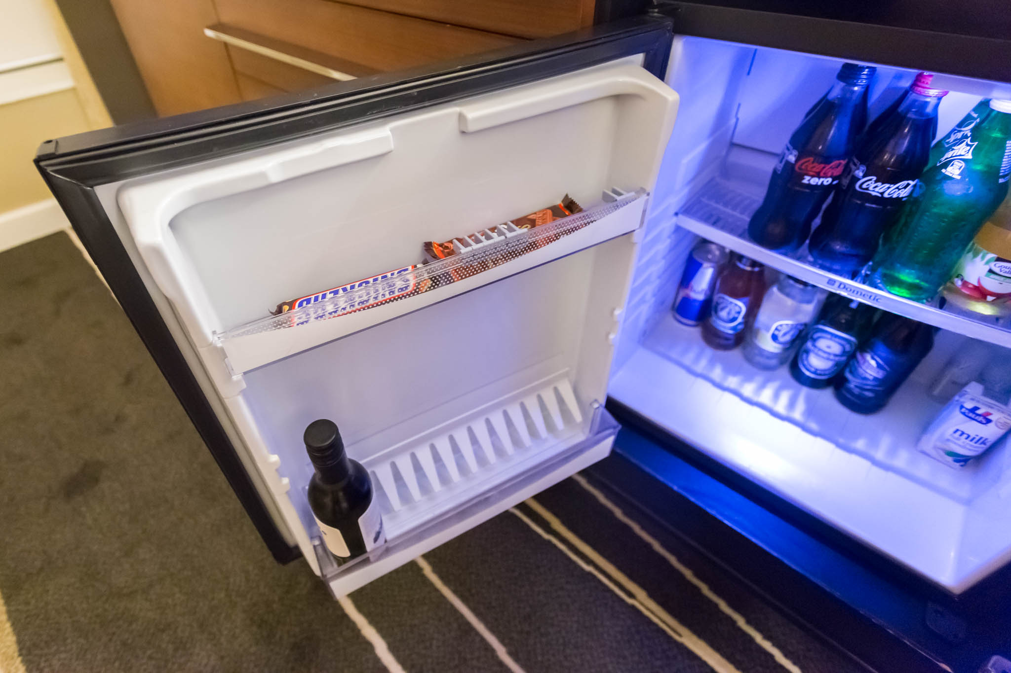 a mini fridge with a bottle of candy and a candy bar