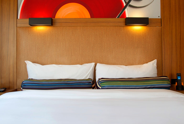 a bed with white sheets and colorful pillows