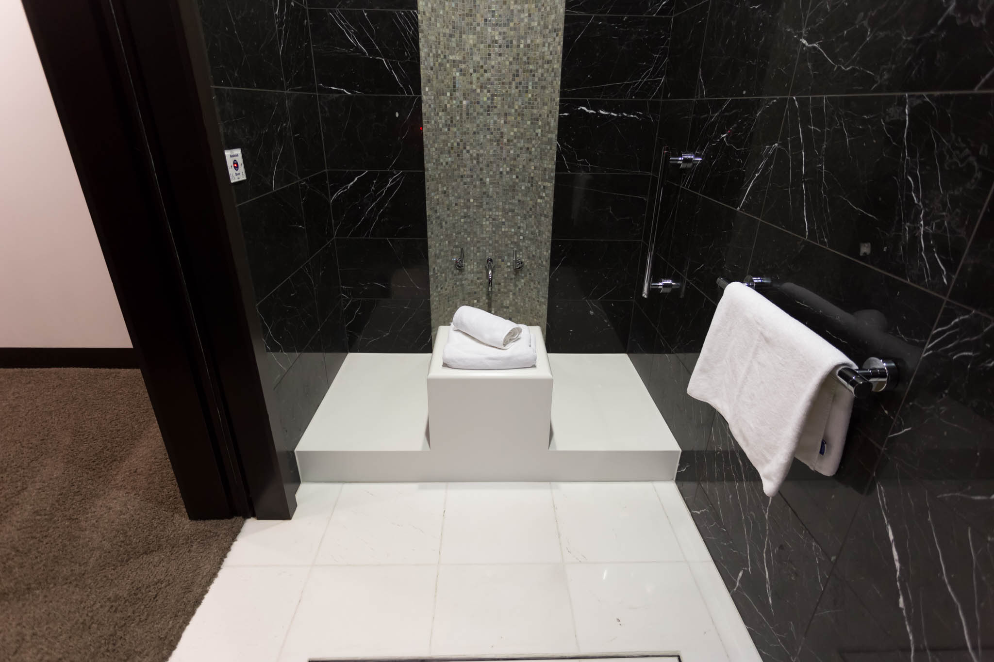 a bathroom with a black tile wall and a white towel on the wall