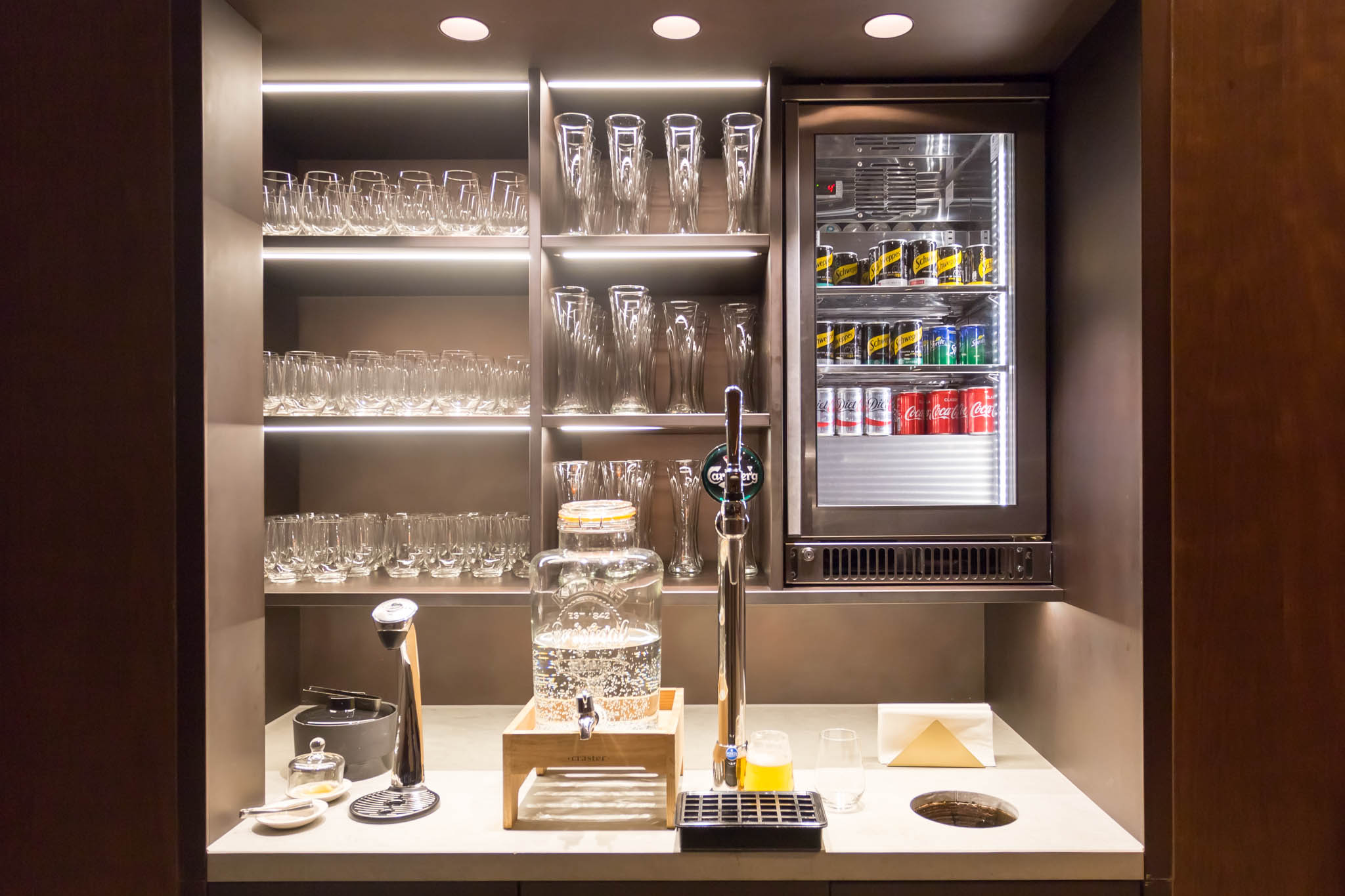 a bar with a beverage dispenser and glasses