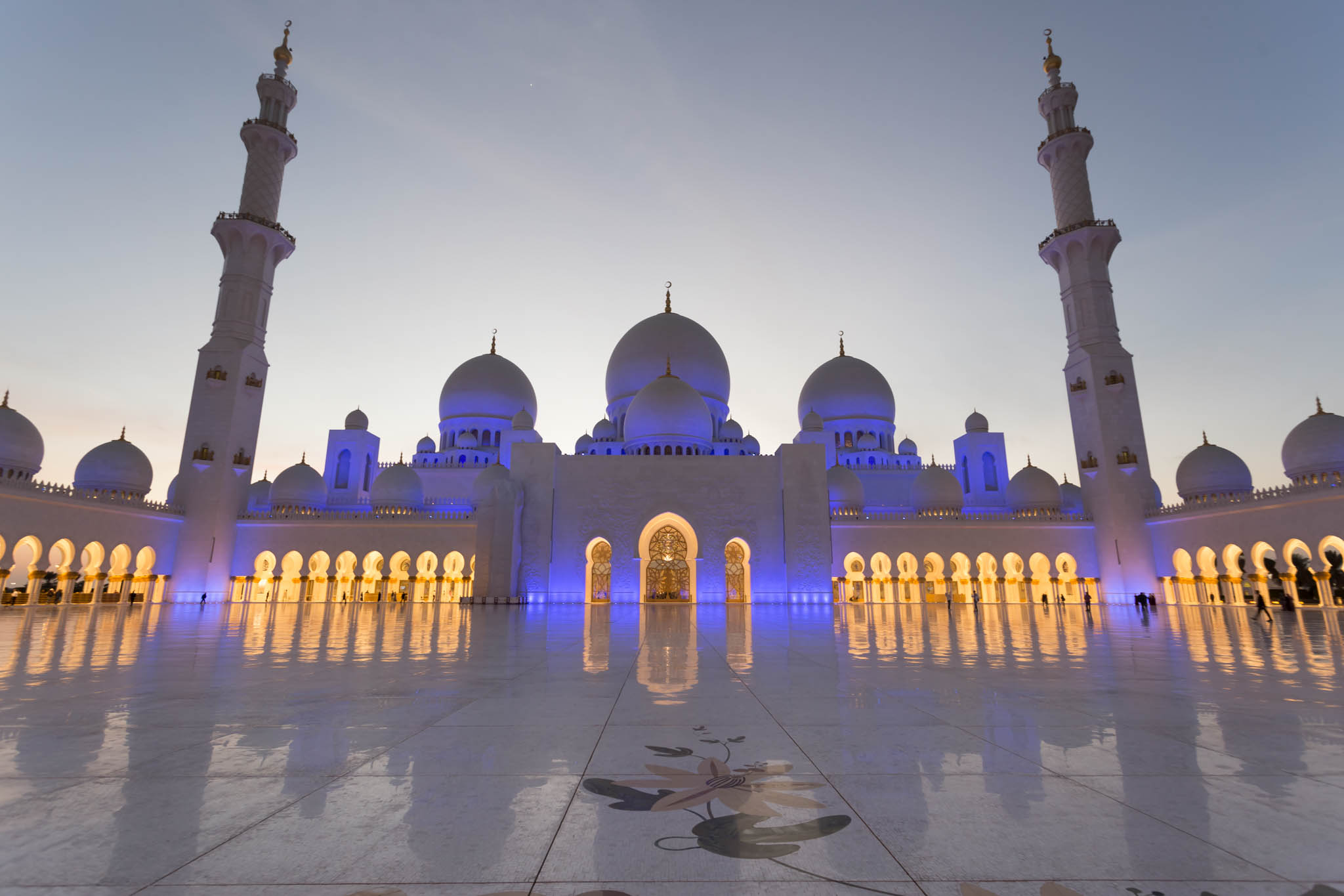 a large white building with domes and towers with Sheikh Zayed Mosque in the background
