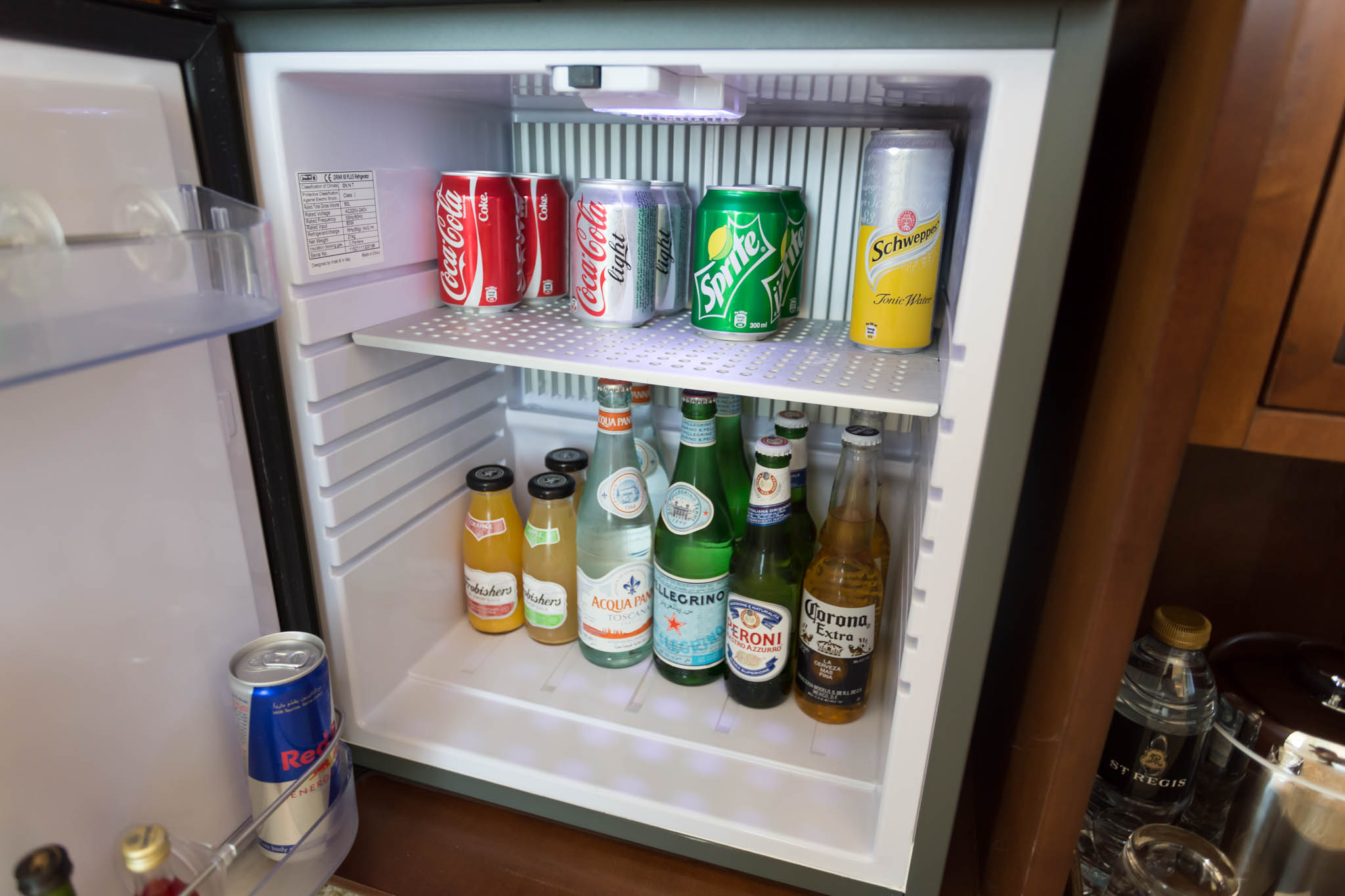 a mini fridge with bottles of soda and other beverages