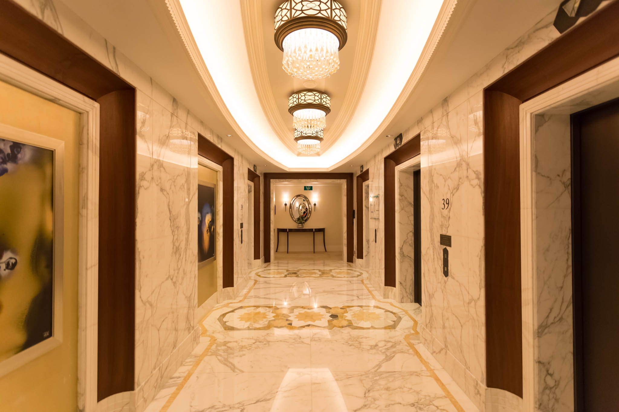 a hallway with marble floor and chandeliers
