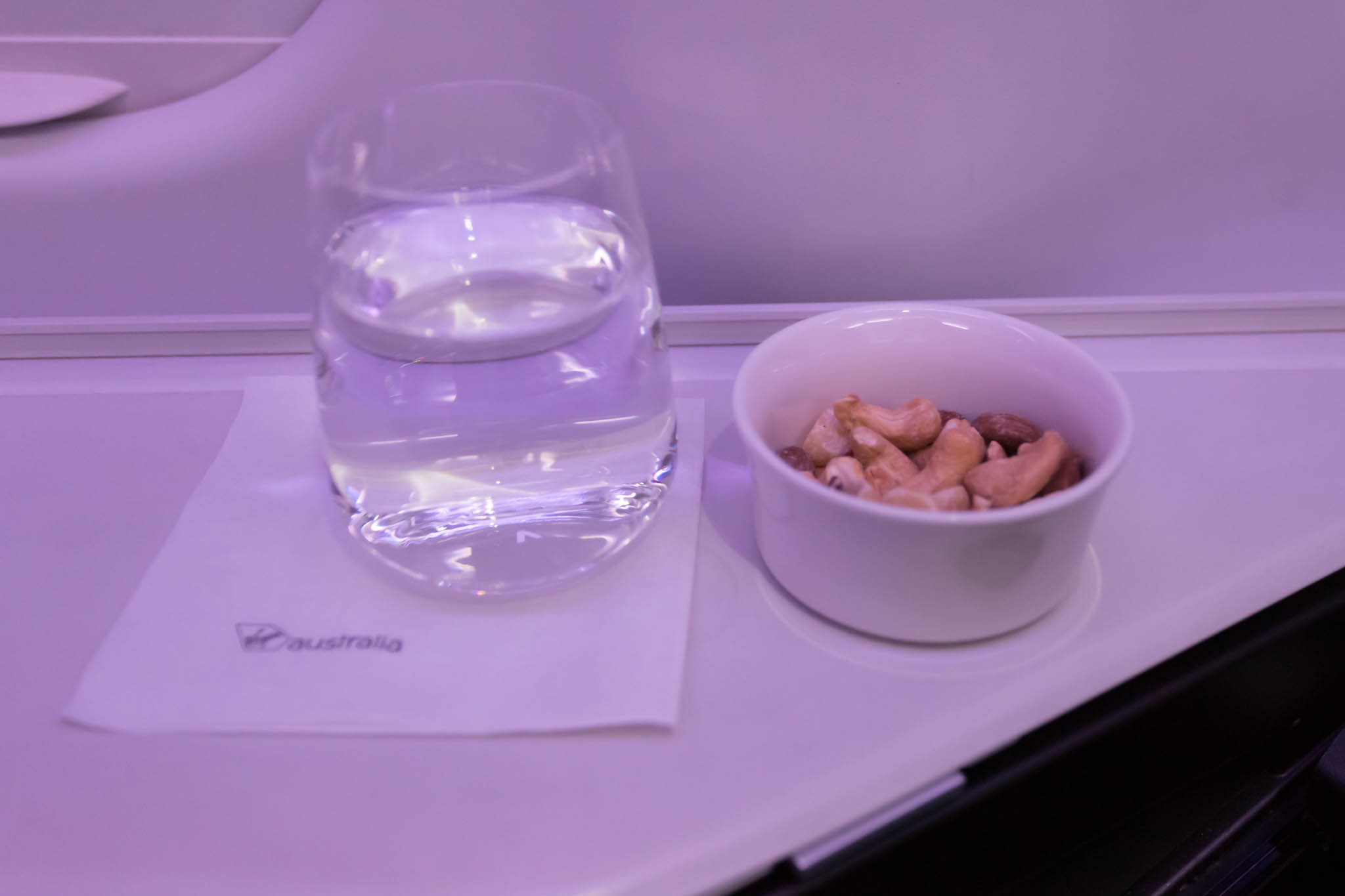 a bowl of nuts and a glass of water on a tray