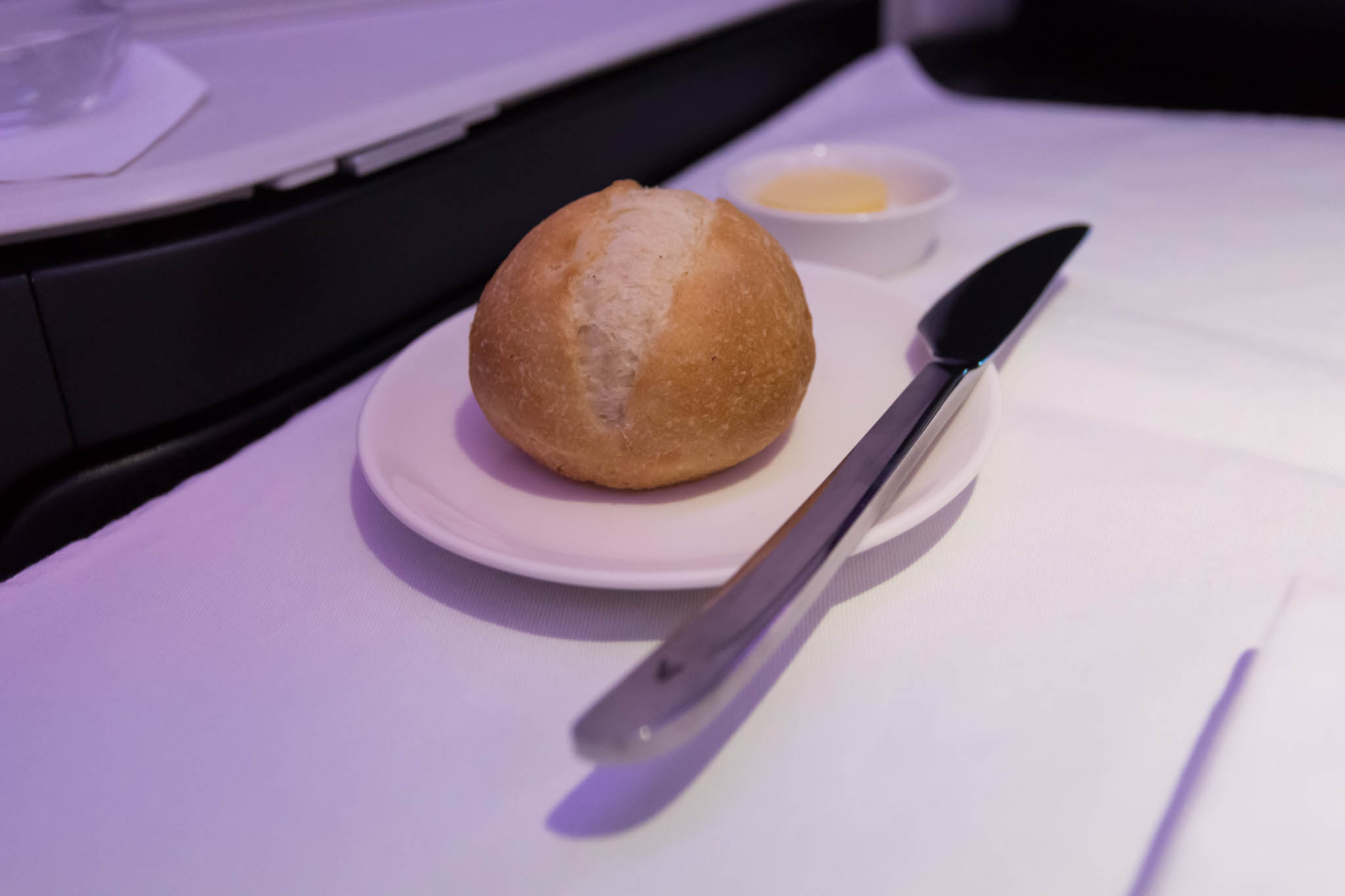 a plate with a roll on it and a knife on a table