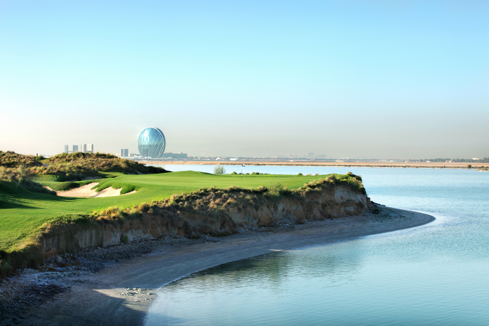 a golf course with a body of water and a large ball in the distance