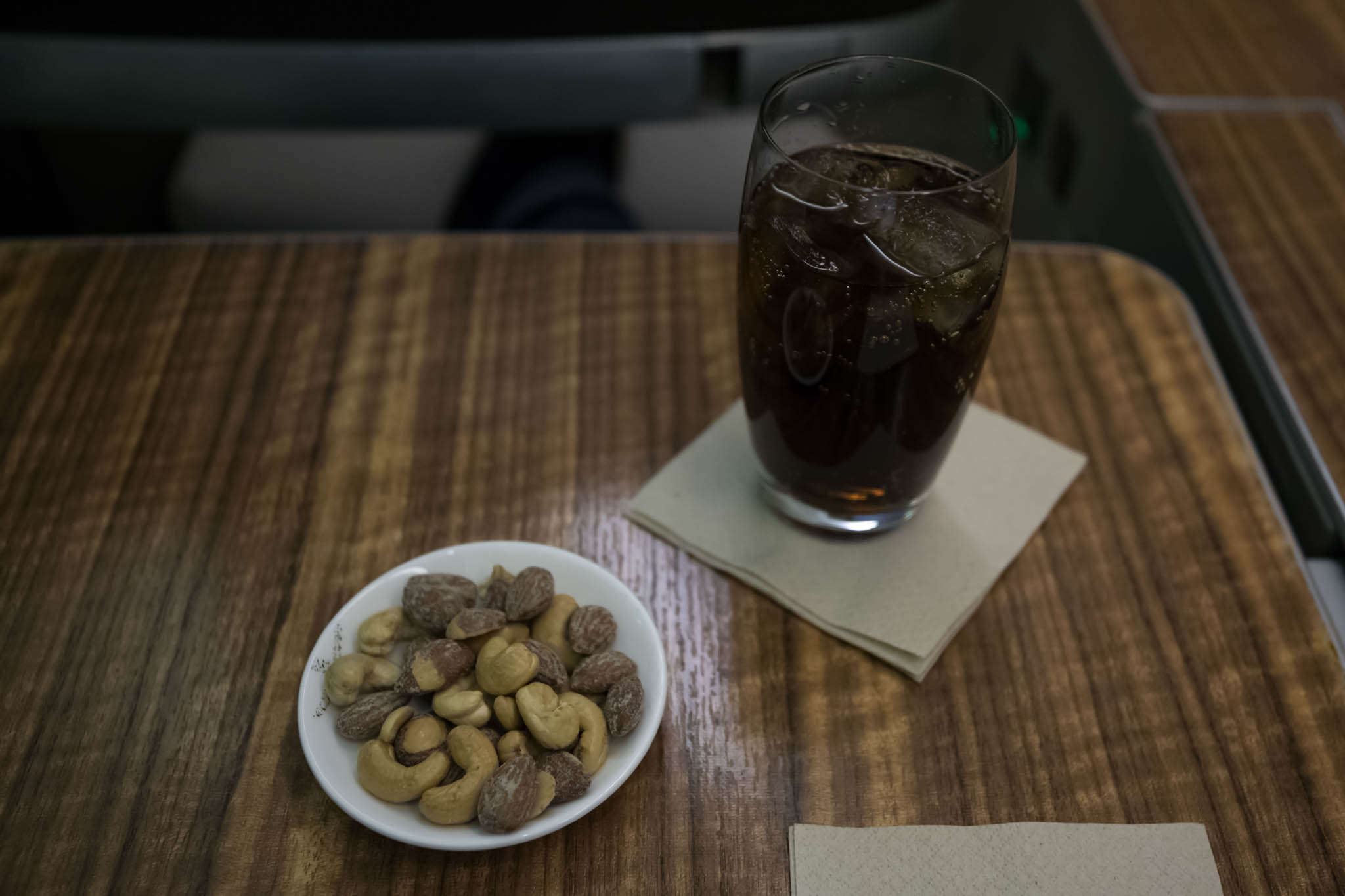 a plate of nuts and a glass of soda on a table
