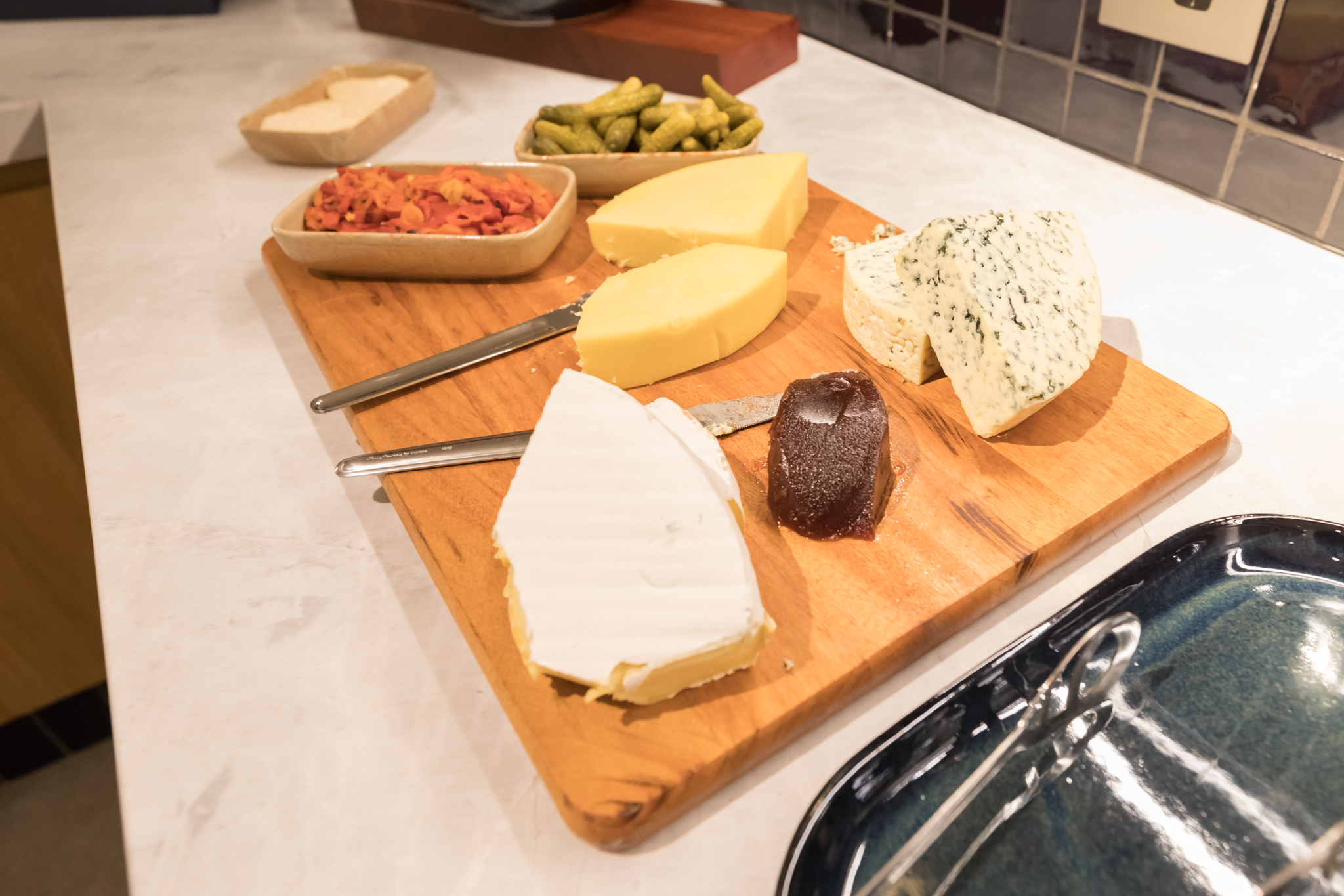 a wooden board with different types of cheese and various food