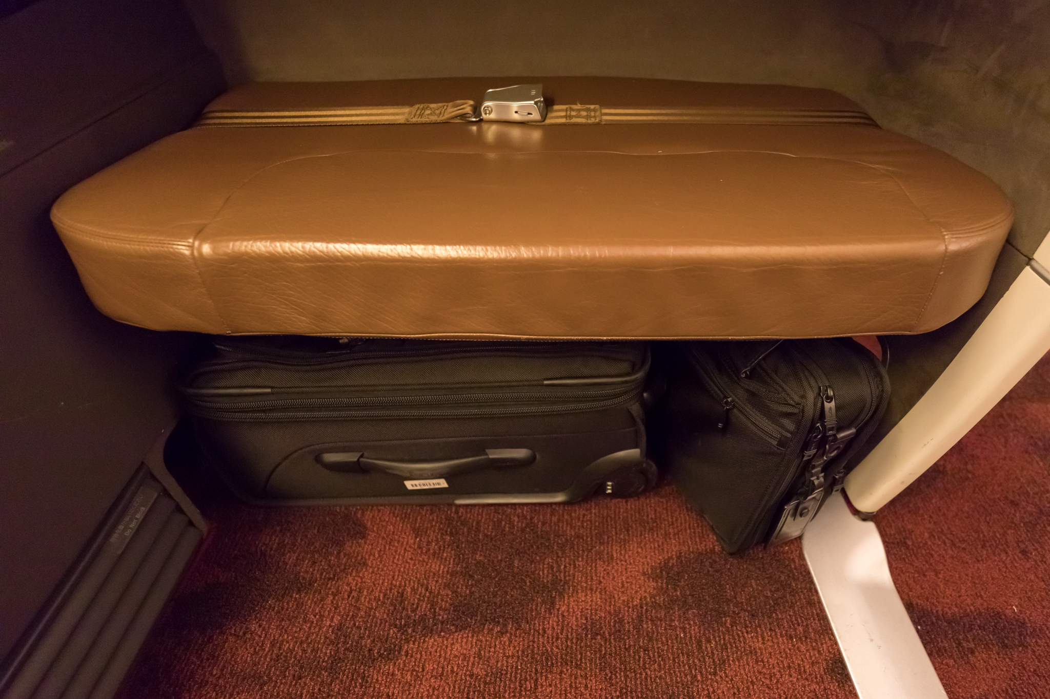 a brown leather suitcase with a brown leather seat on top of a brown carpeted floor