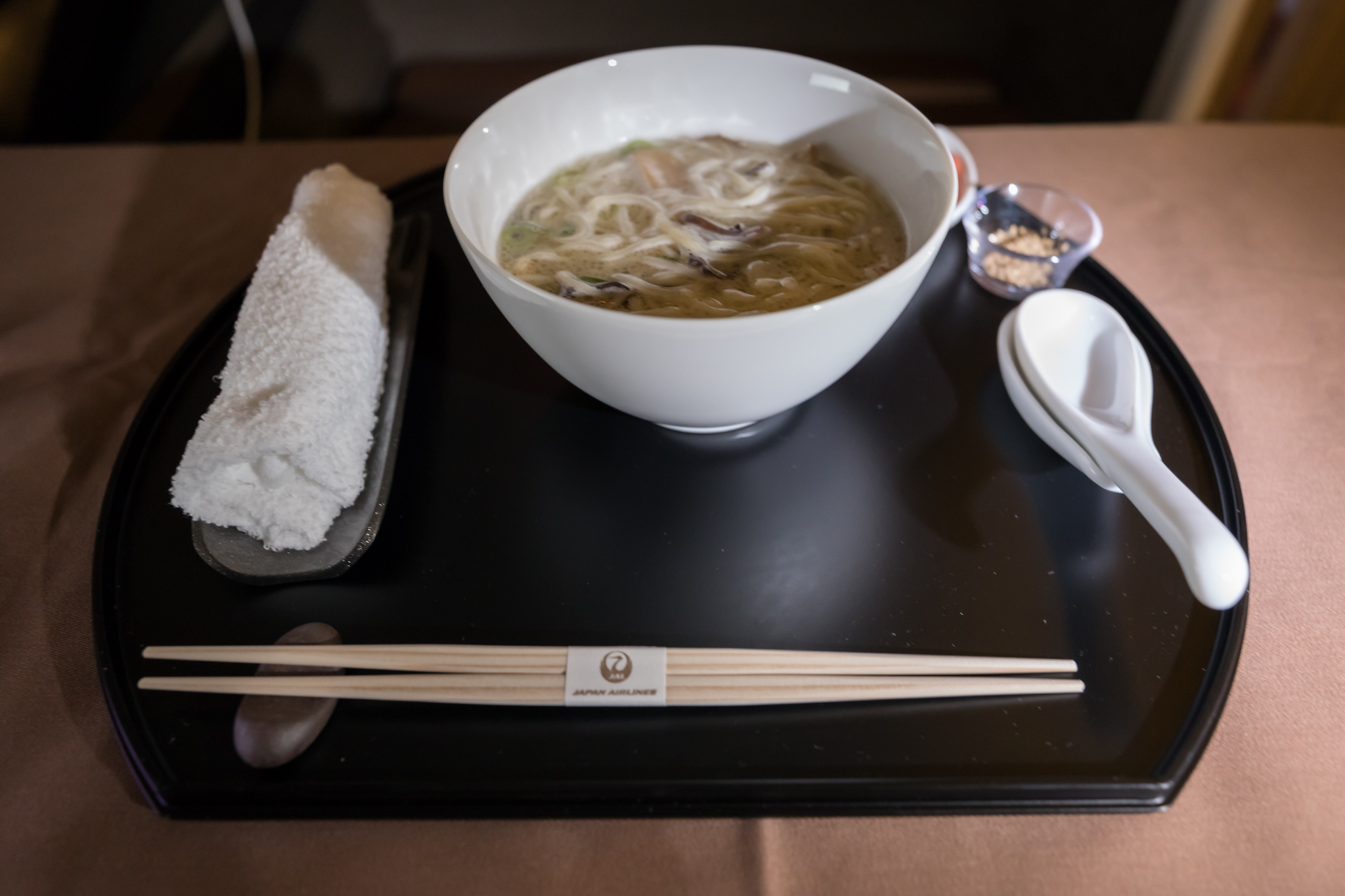 a bowl of soup and chopsticks on a tray