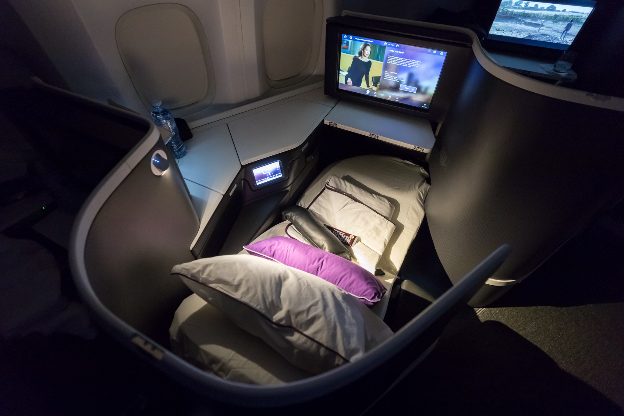 a bed with a television and pillows in a seat