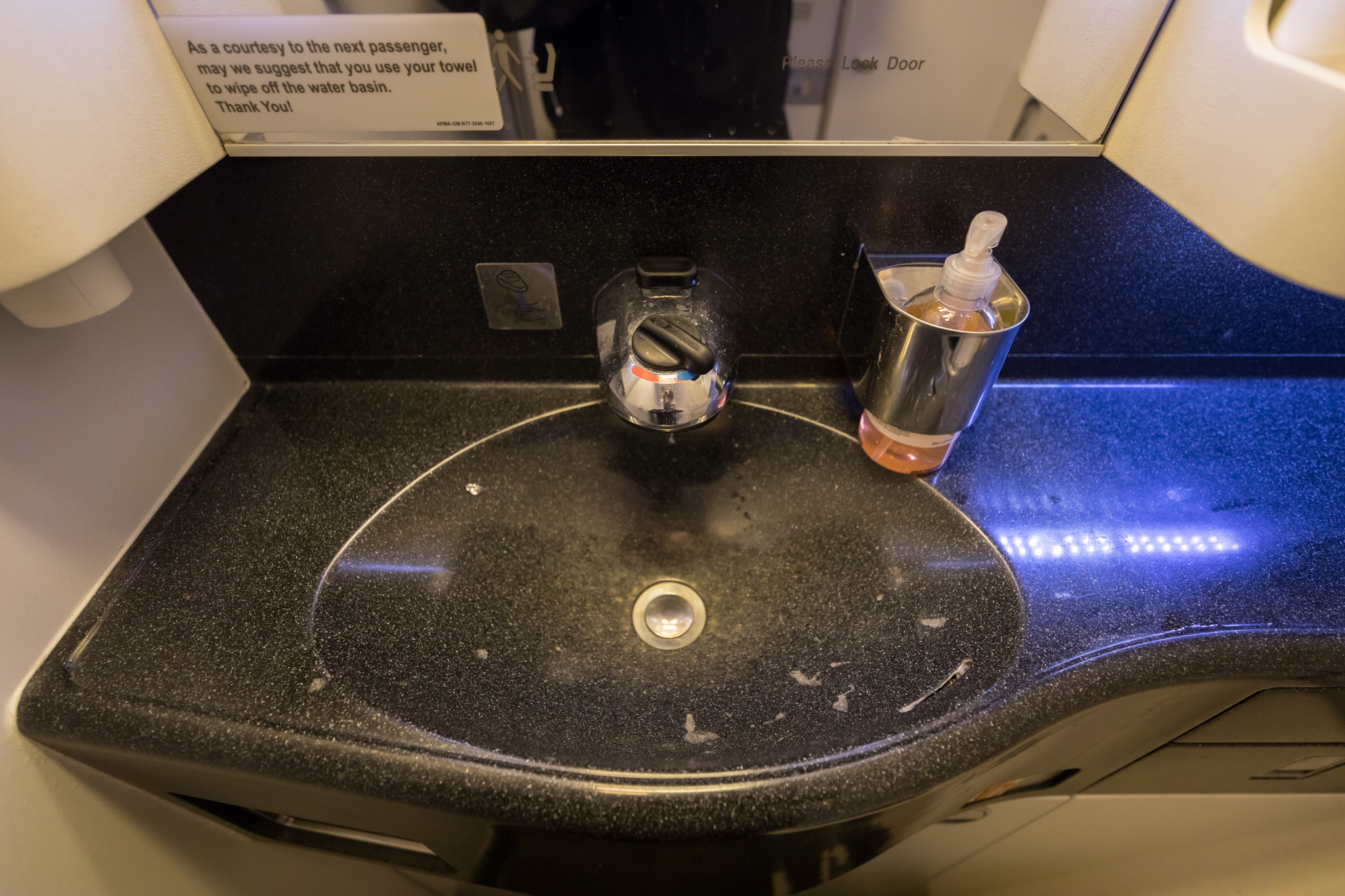 a sink with soap dispenser and a sign