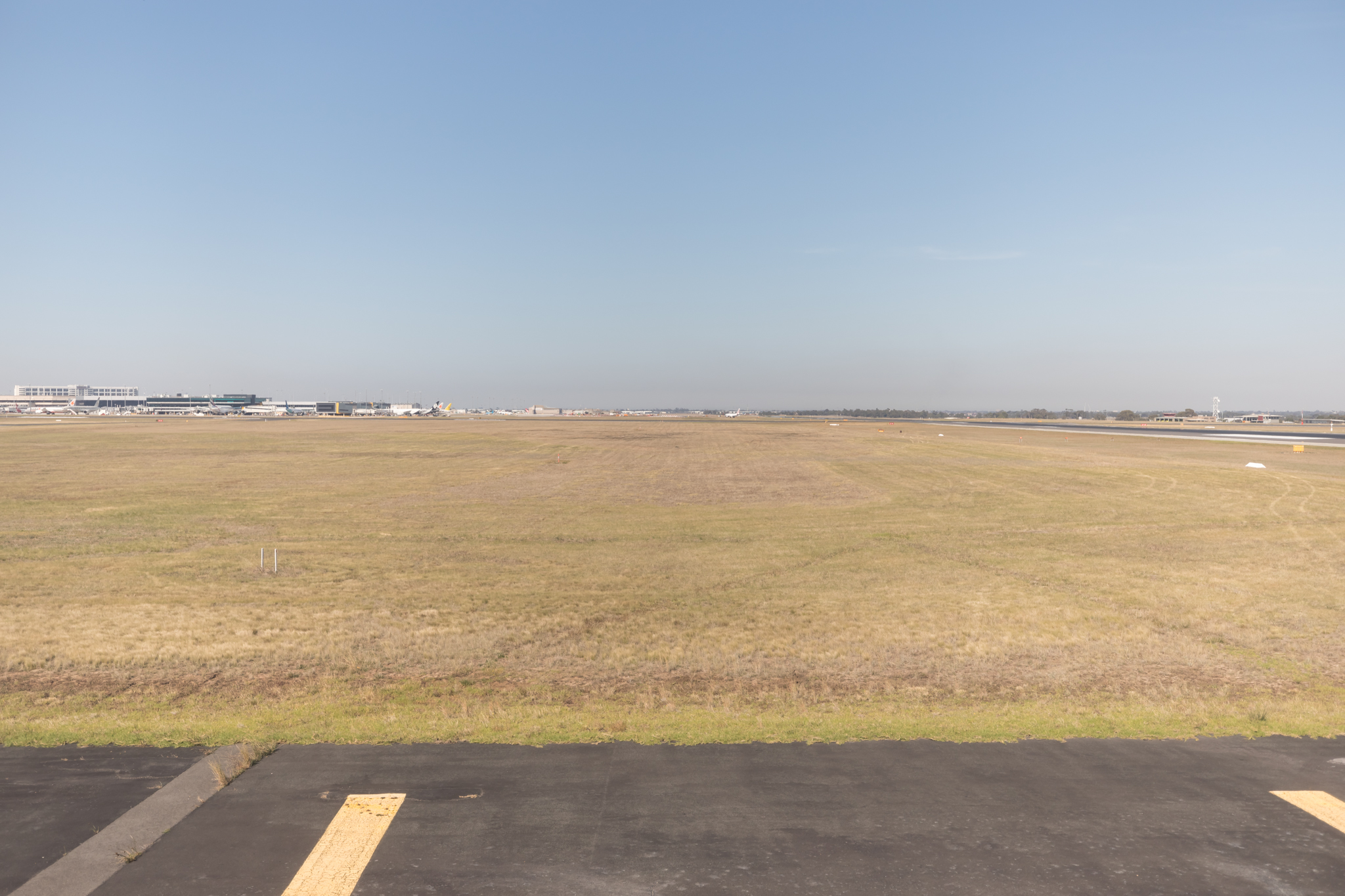 a large field with a runway and buildings in the background