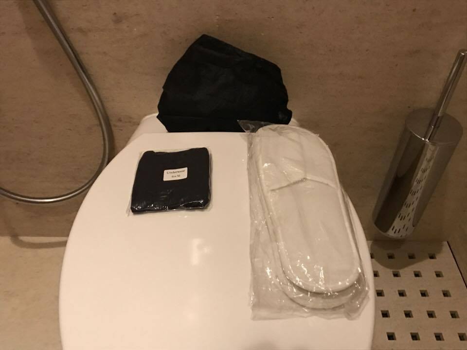 a toilet seat with a black towel and a black slipper on it