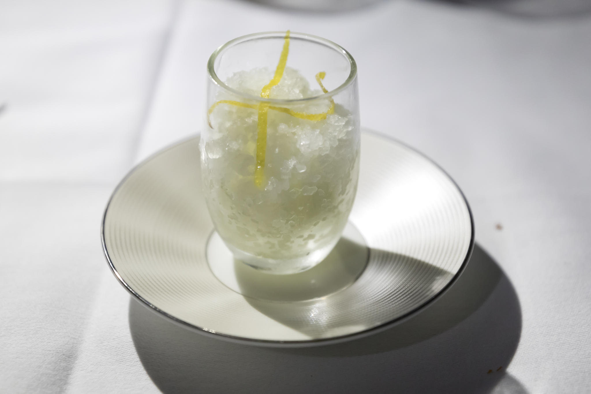 a glass with a lemon peel on a plate