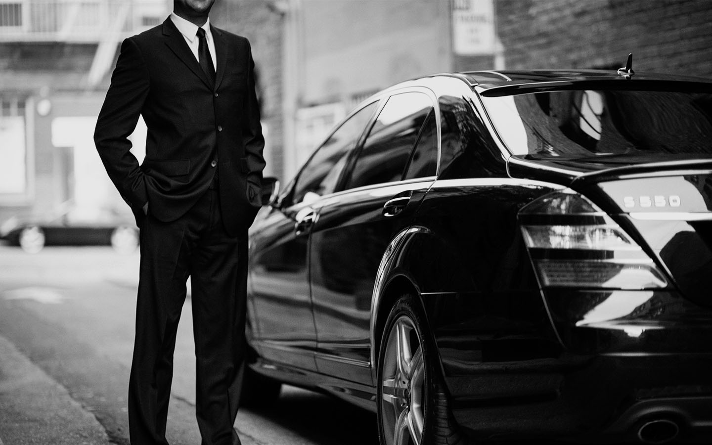 a man in a suit and tie standing next to a car