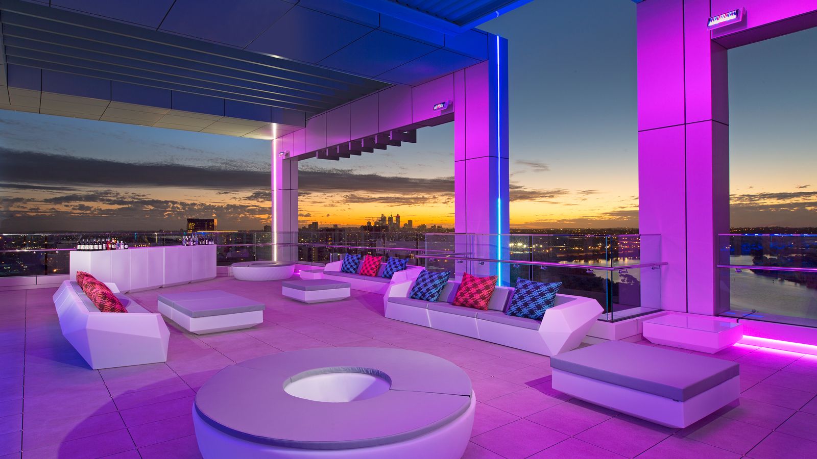 a rooftop patio with colorful pillows and a view of a city