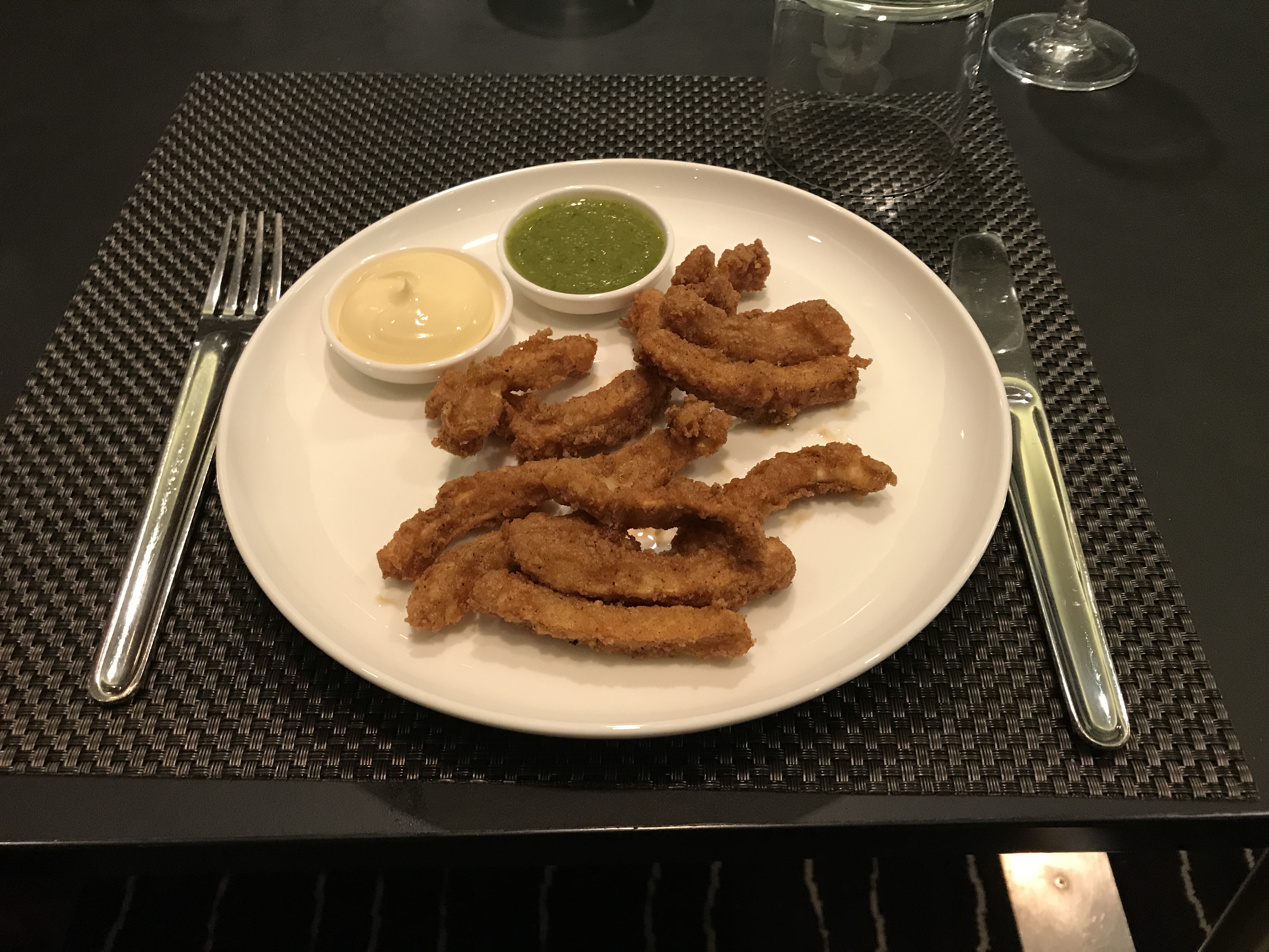 a plate of fried food with sauces on a place mat