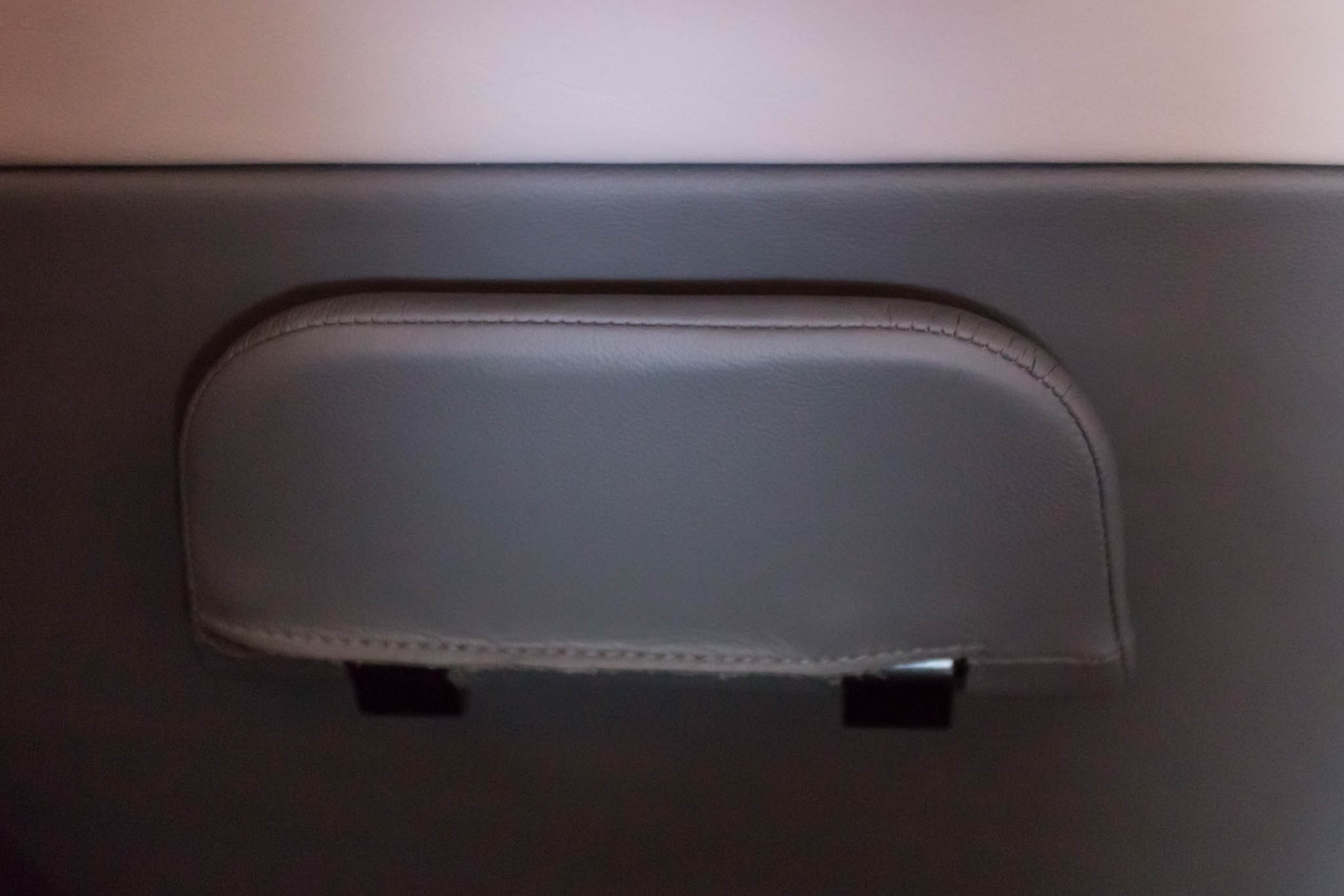 a grey leather seat with a black handle
