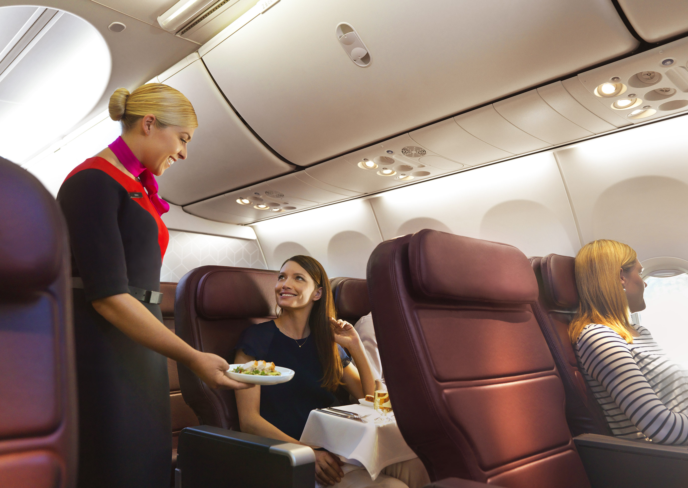 a woman serving food to a group of women in an airplane