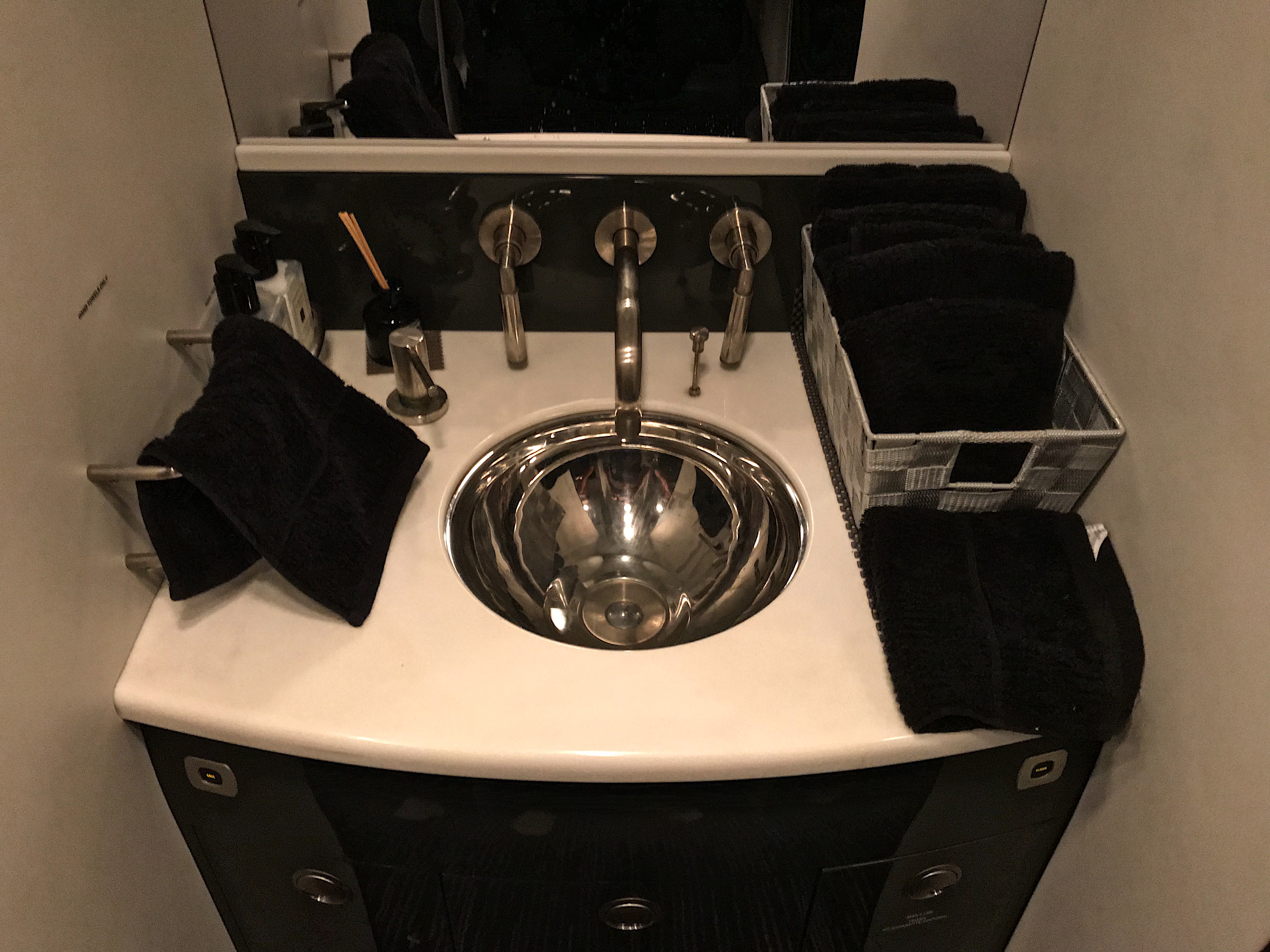 a sink with a mirror and black towels