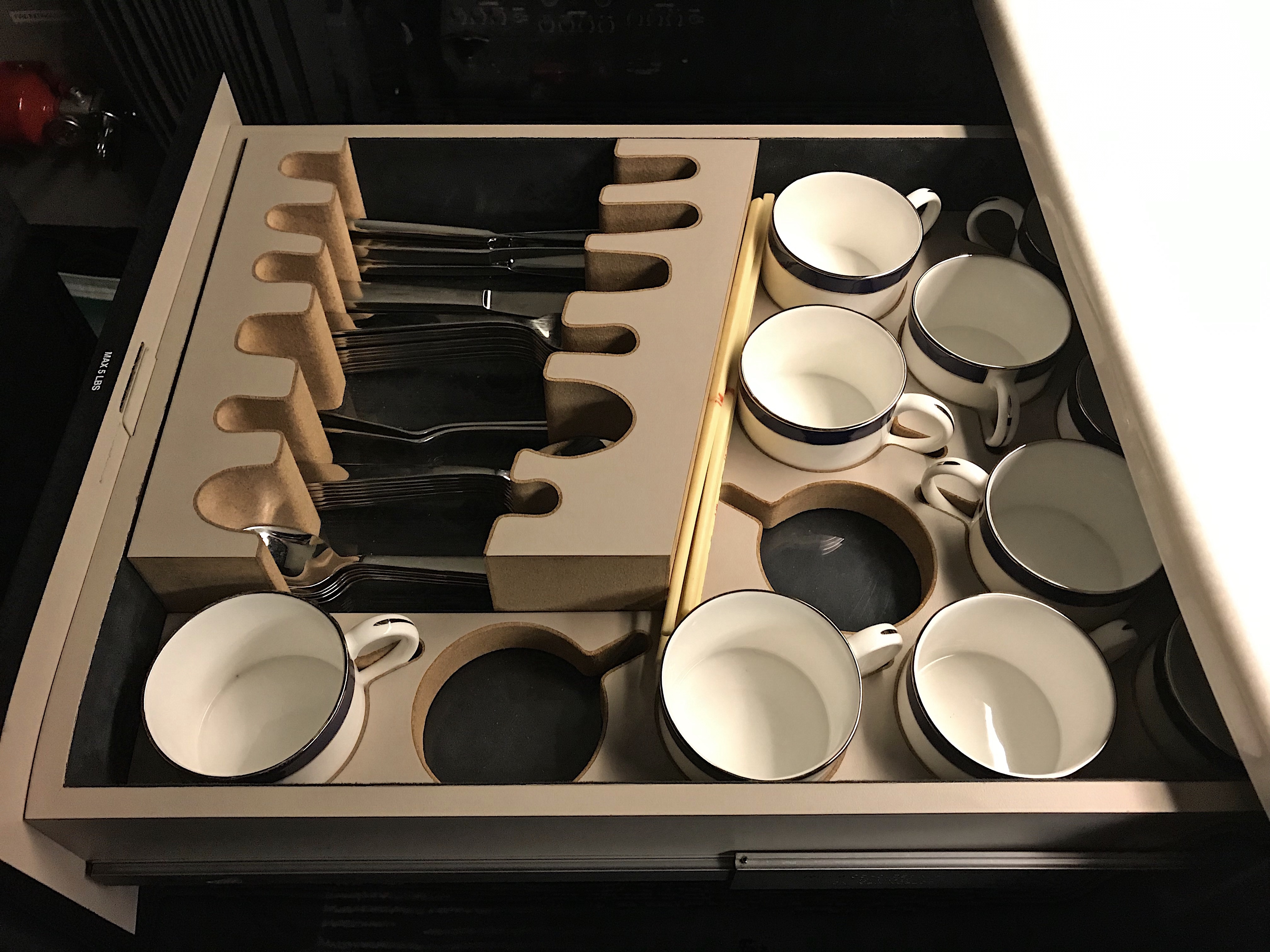 a drawer with white cups and spoons