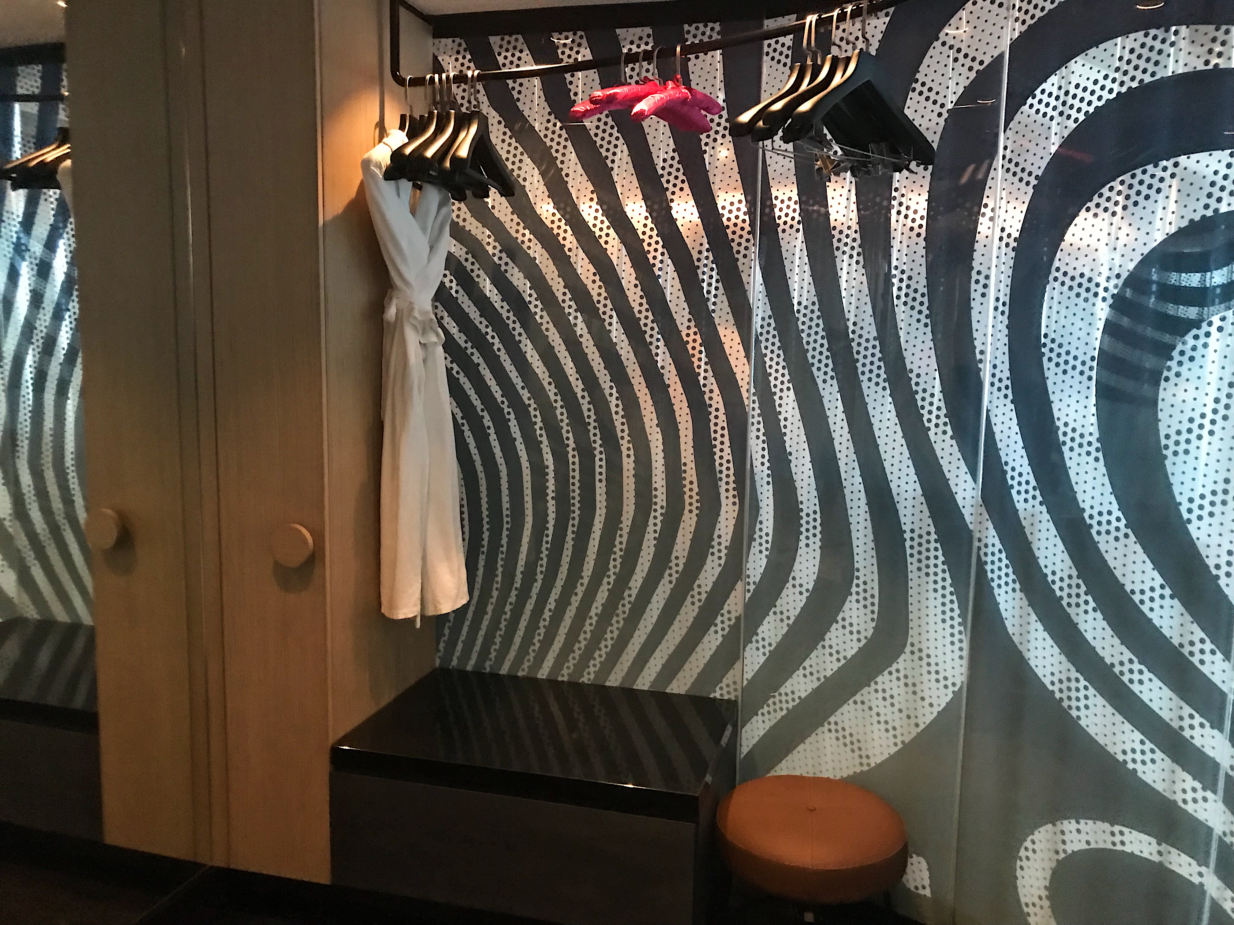 a dressing room with a white robe and a black and white patterned curtain