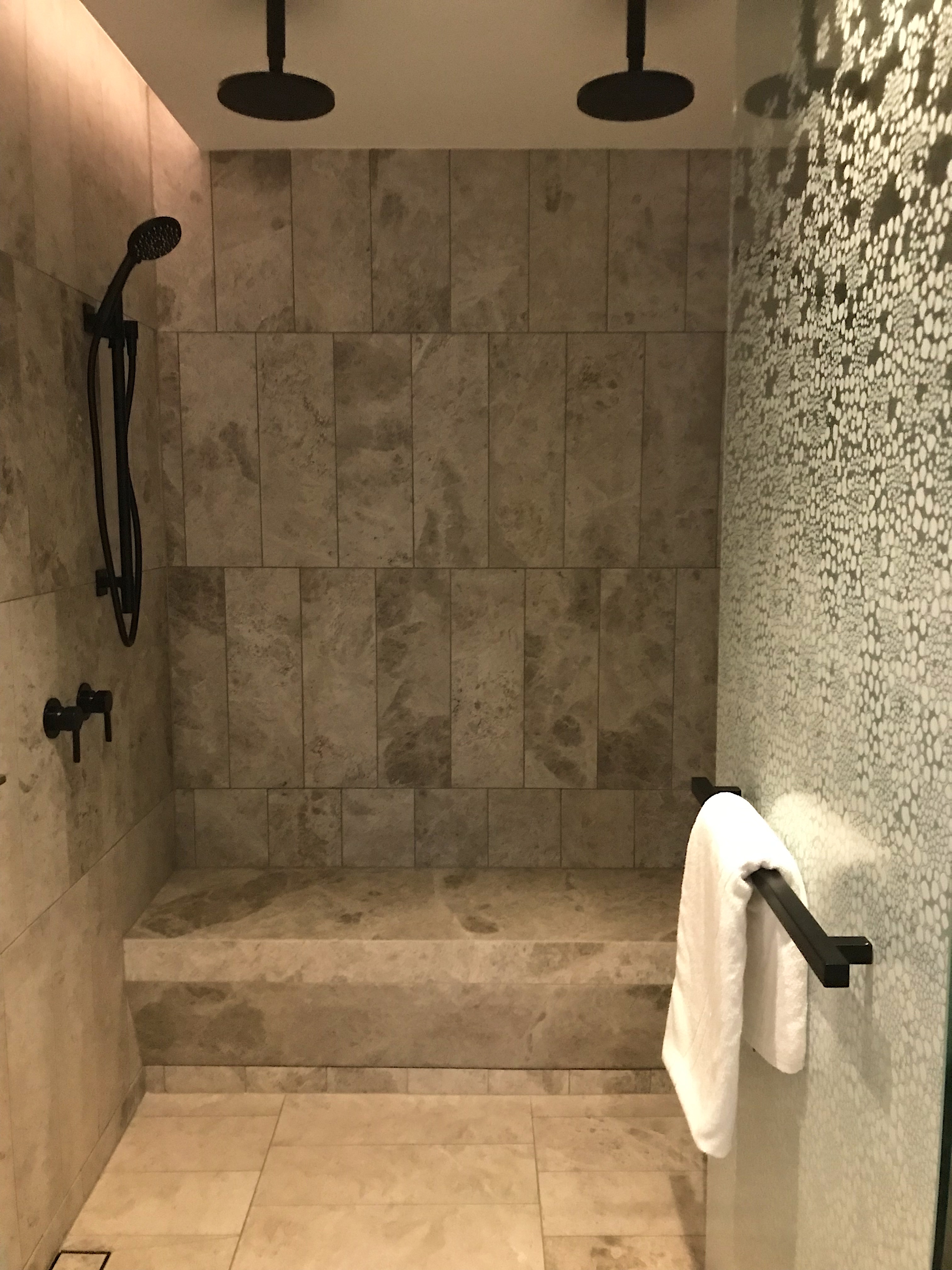 a shower with a stone wall and a white towel on a bar