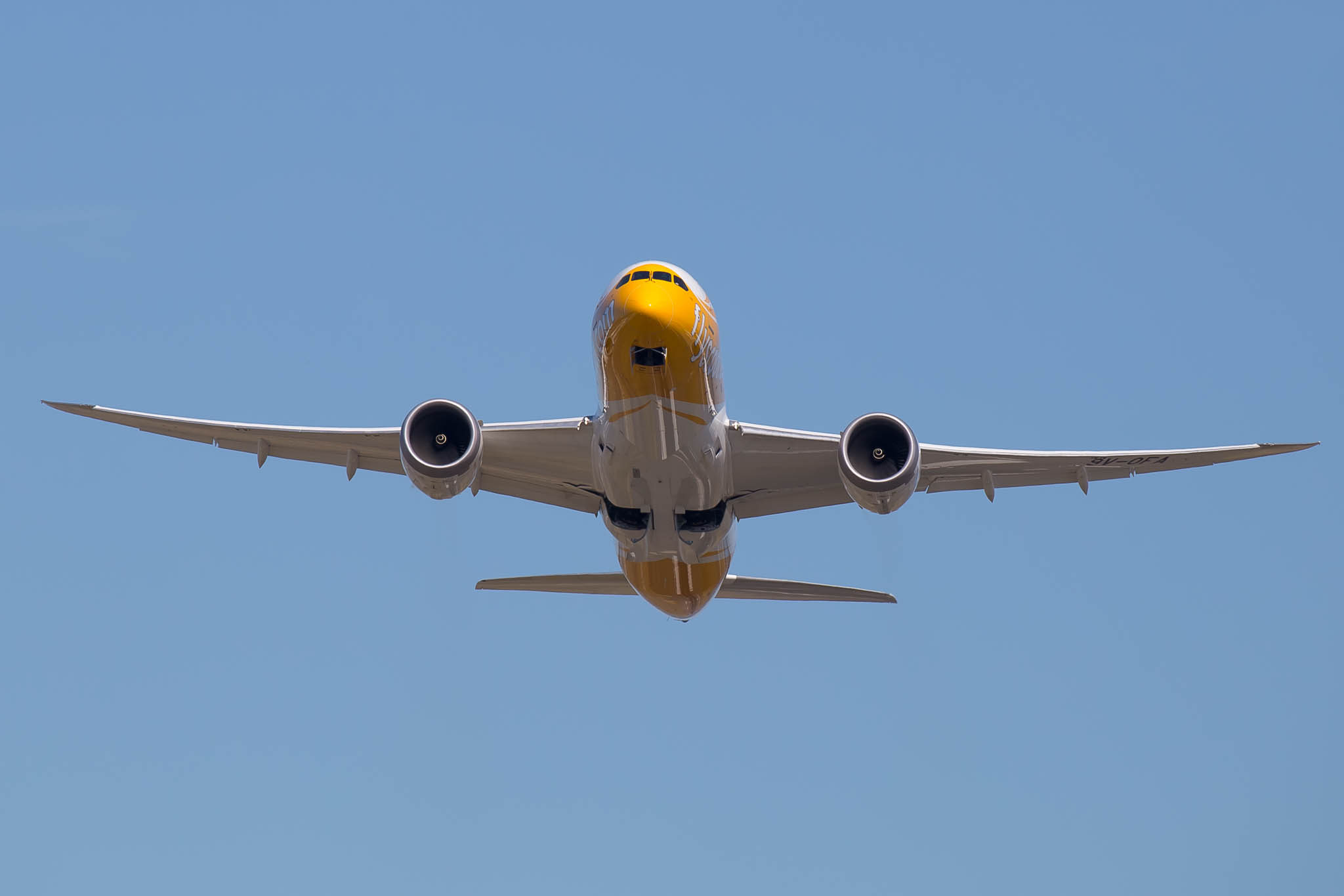 a yellow and white airplane flying in the sky