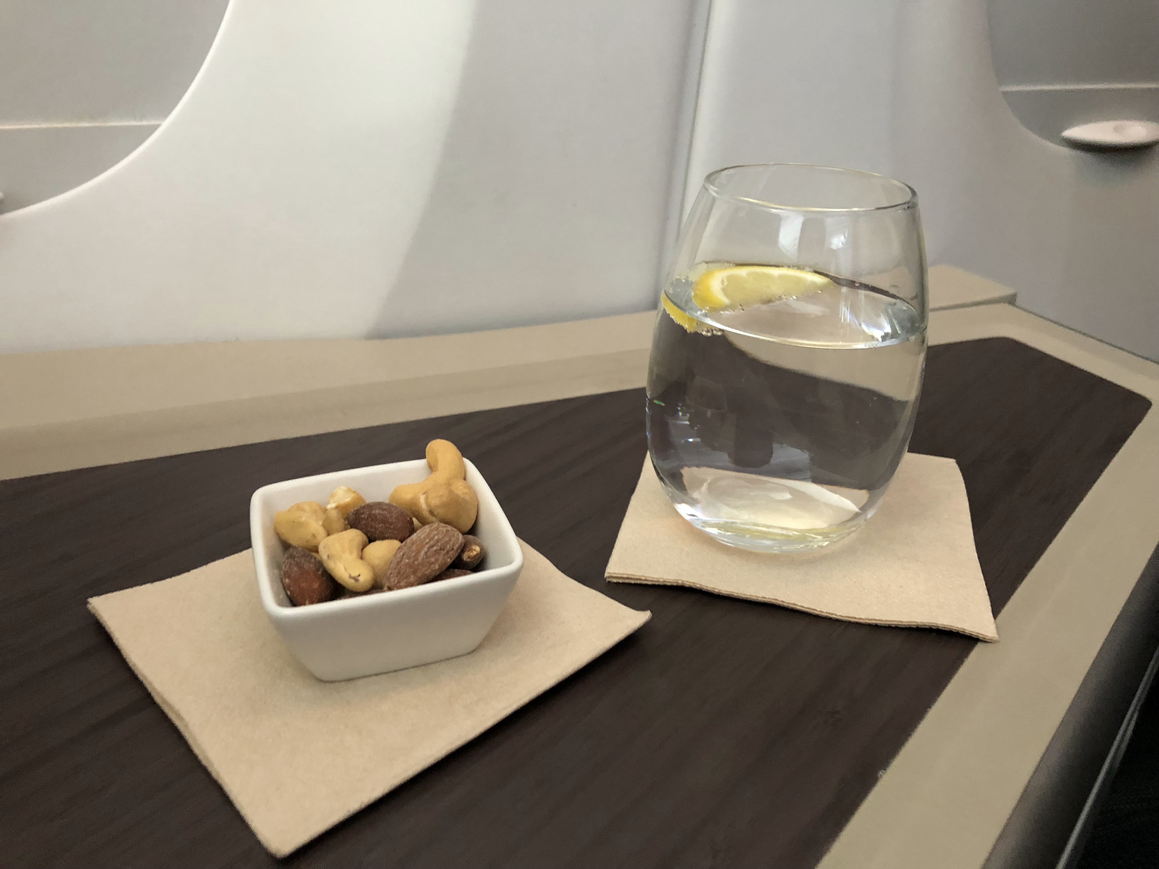 a glass of water and a bowl of nuts on a table
