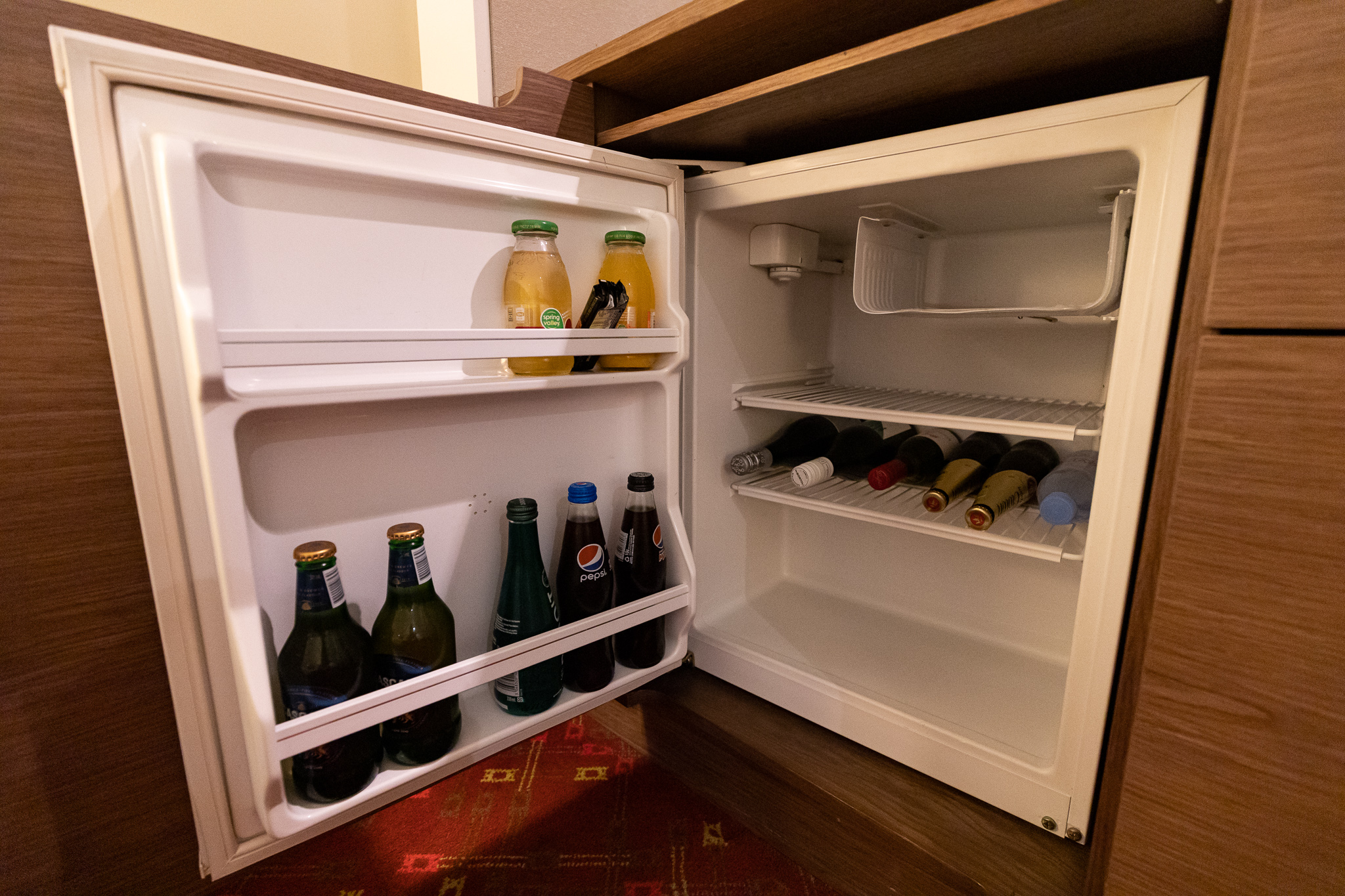 a mini fridge with bottles of beer inside