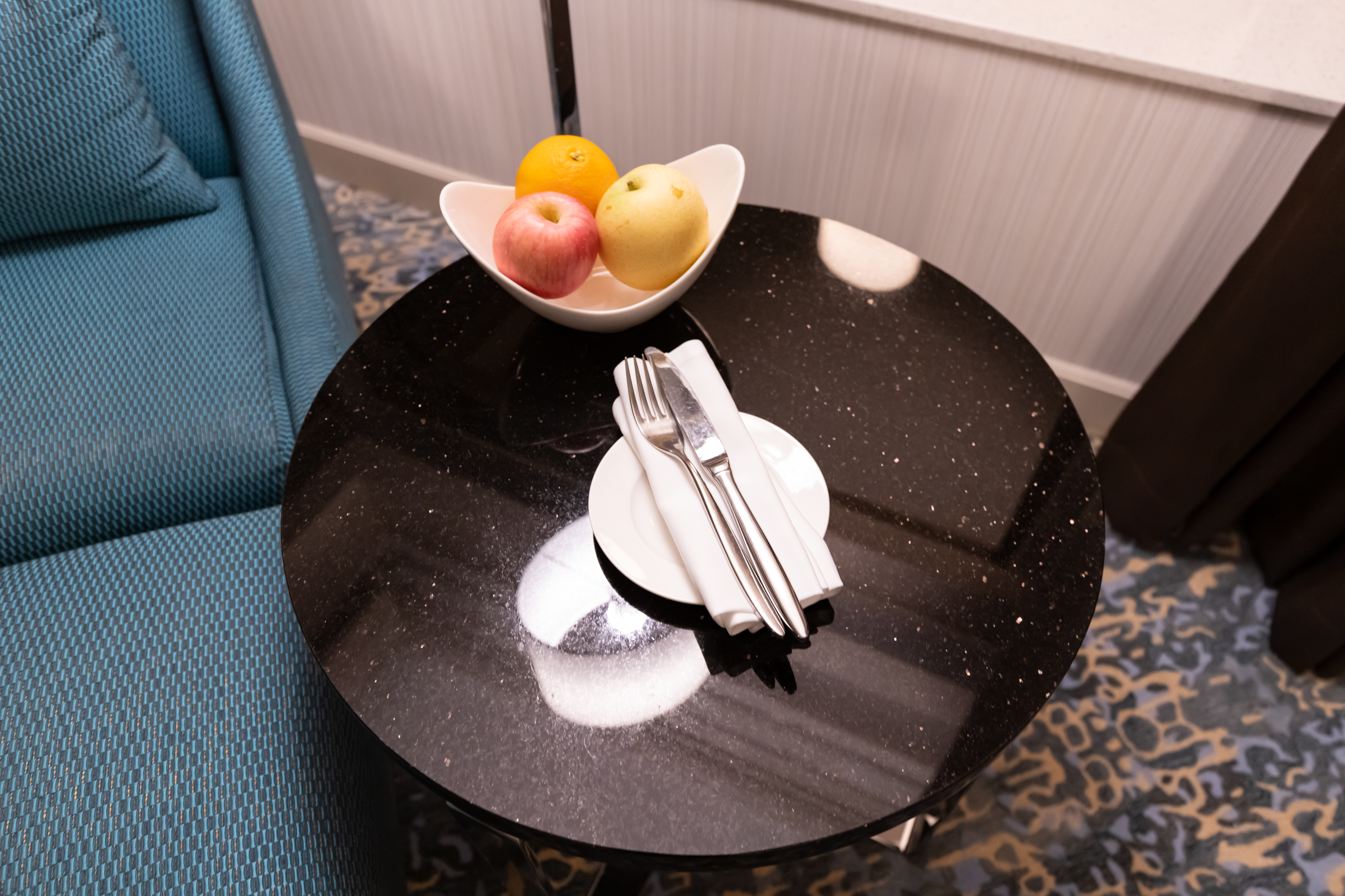 a bowl of fruit and utensils on a table
