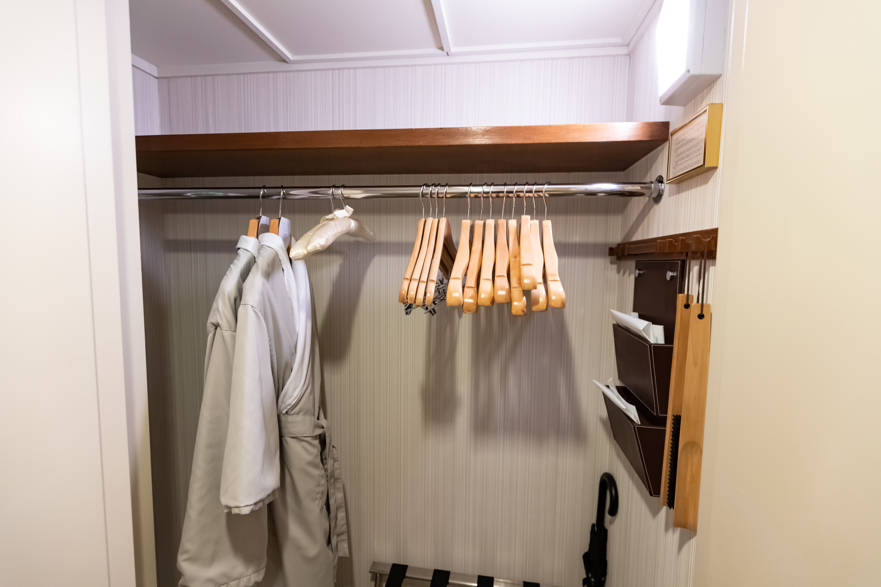 a coat rack with swingers and a coat on a rail