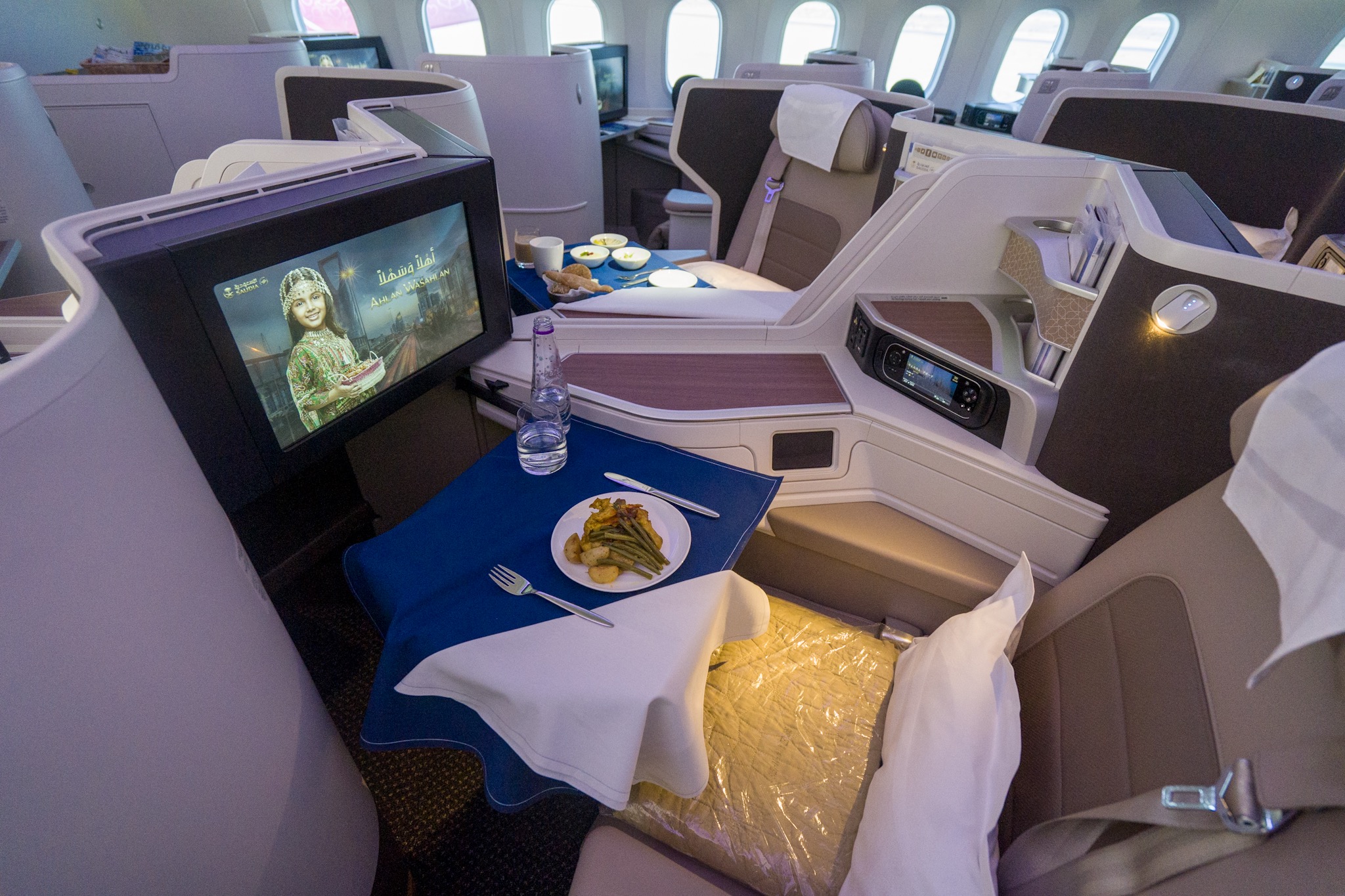 a table with food and a television in the middle of the seat of an airplane
