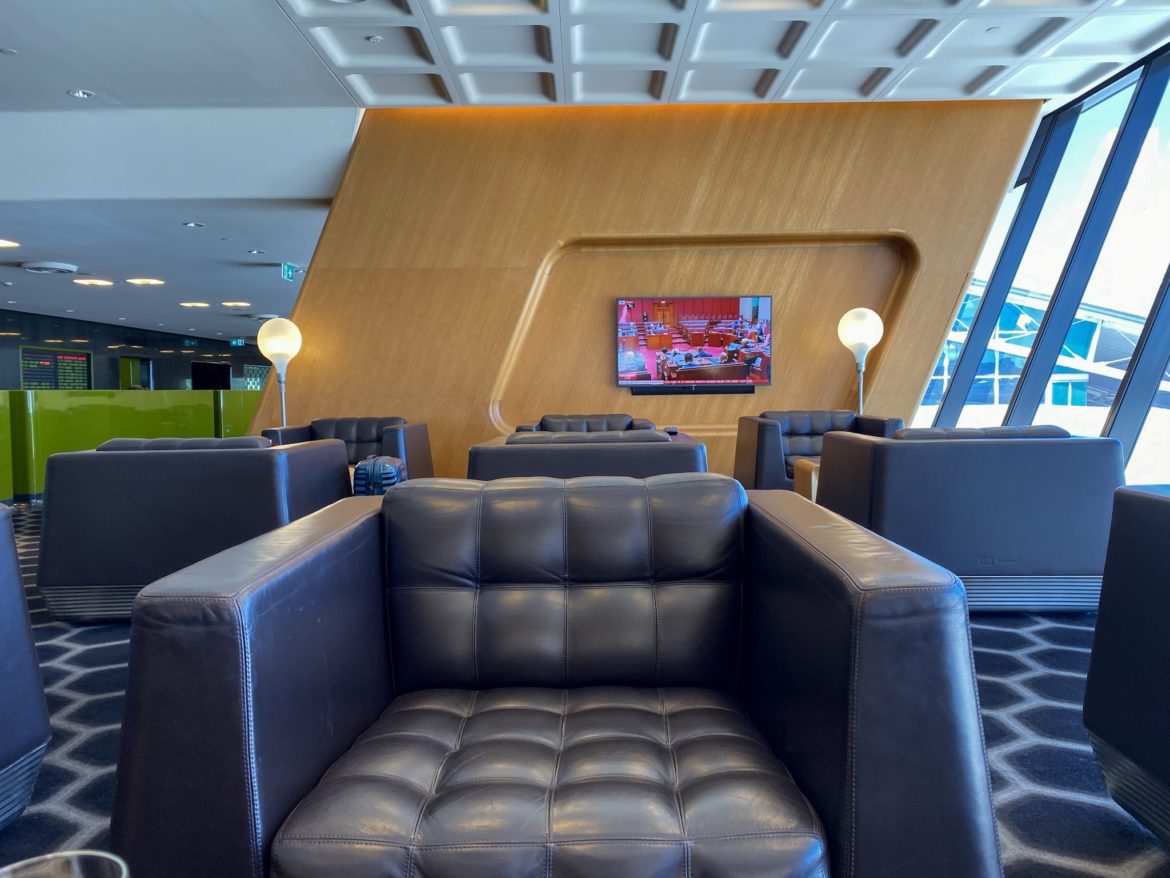 a black leather chair in a room with a television on the wall