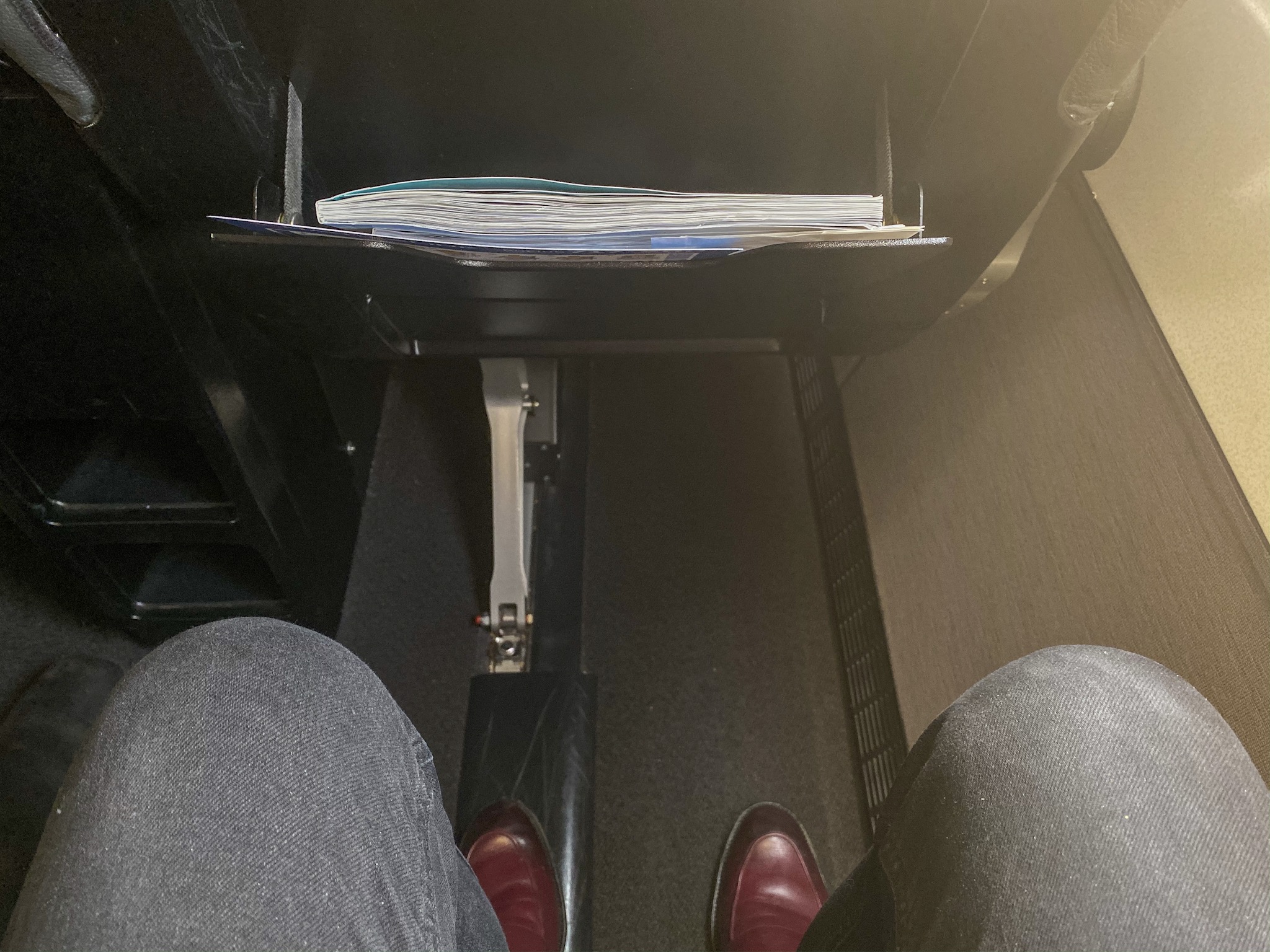 a person's legs and a folder in a seat