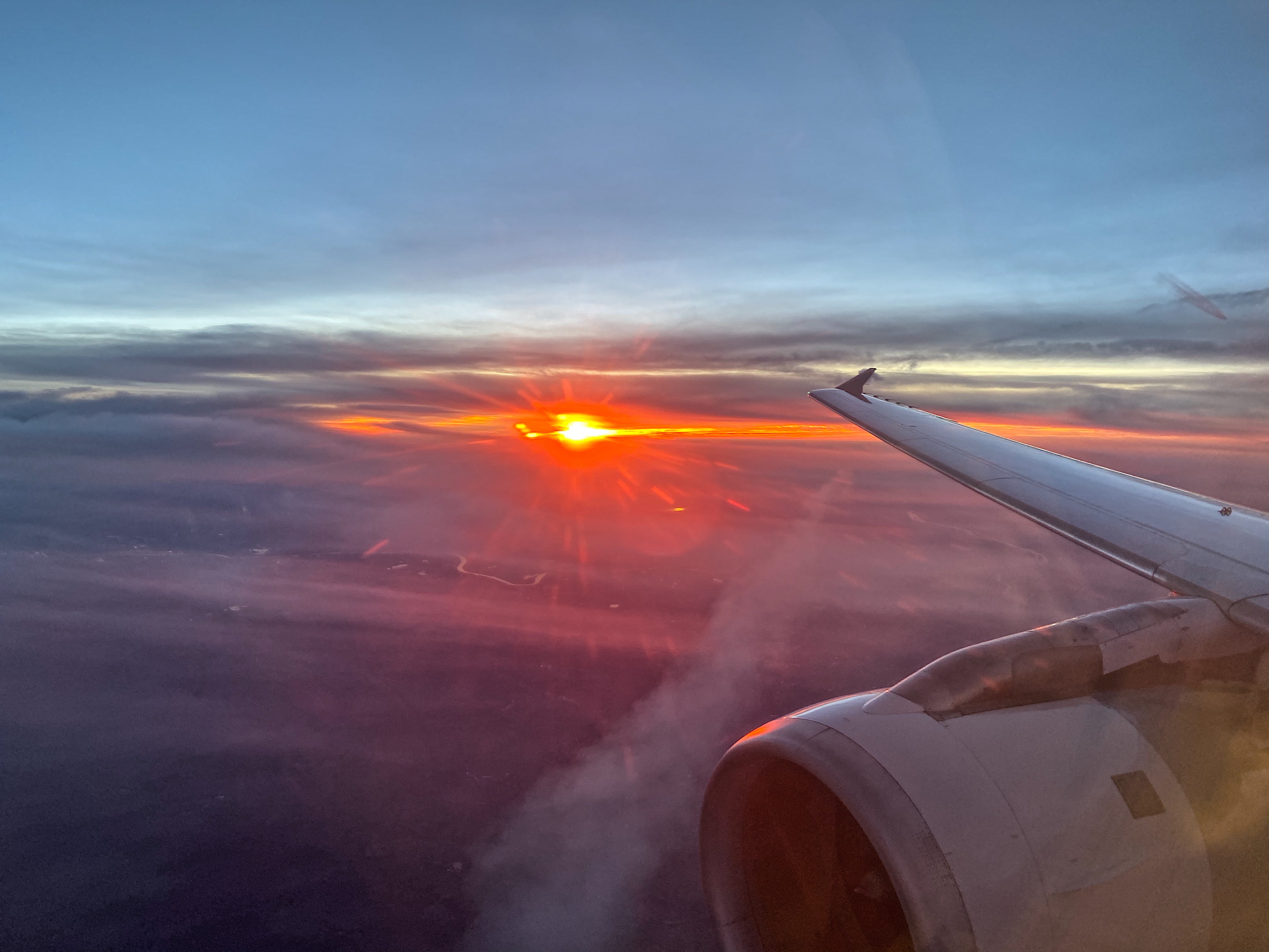an airplane wing and the sun in the sky