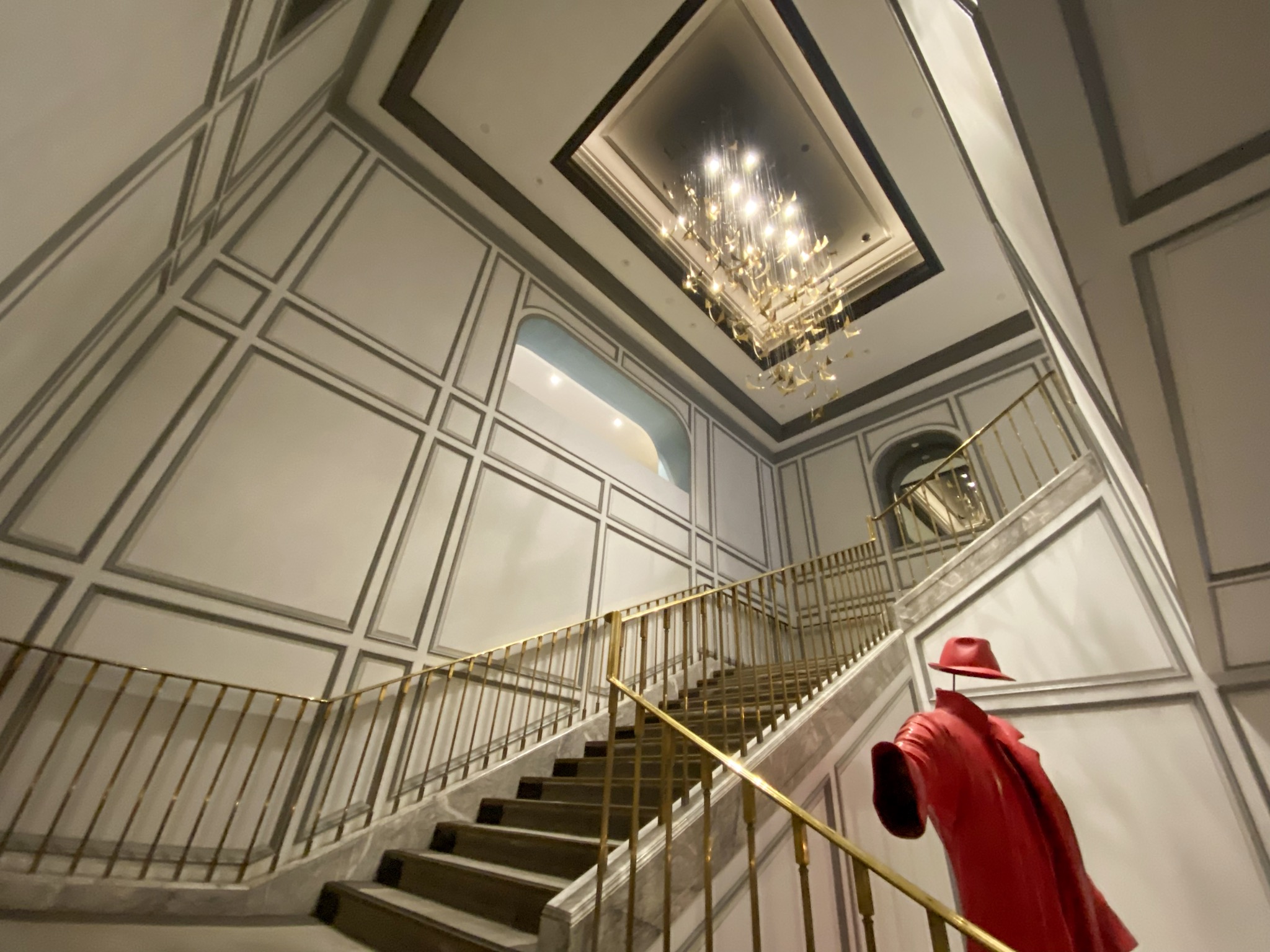 a staircase with a red coat and a chandelier