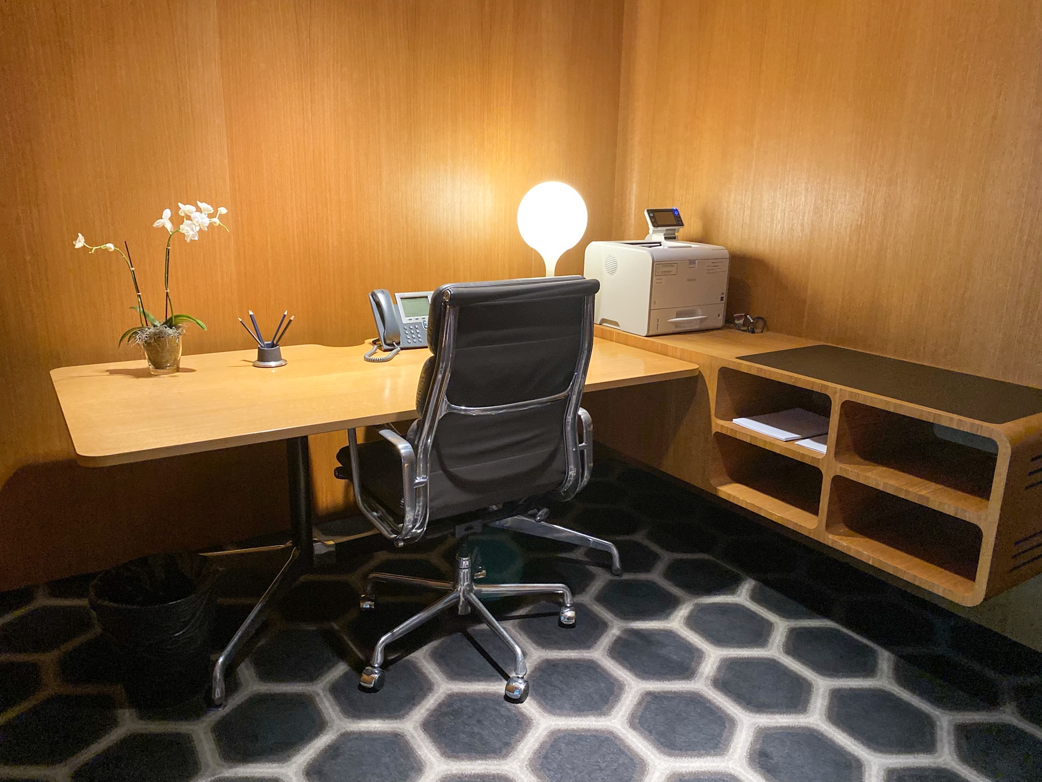 a desk with a chair and a lamp in a room