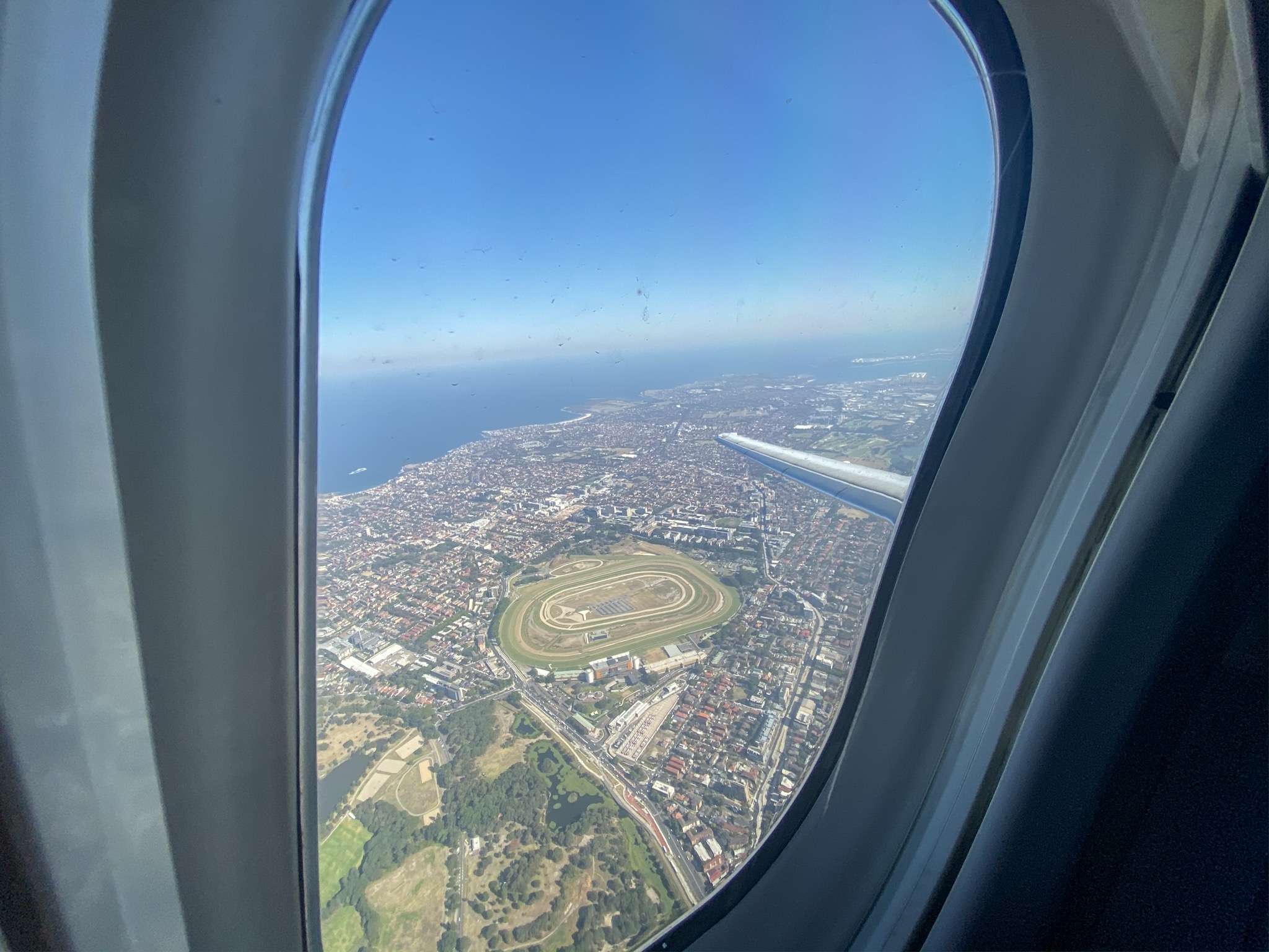 an airplane window with a view of a city and a body of water