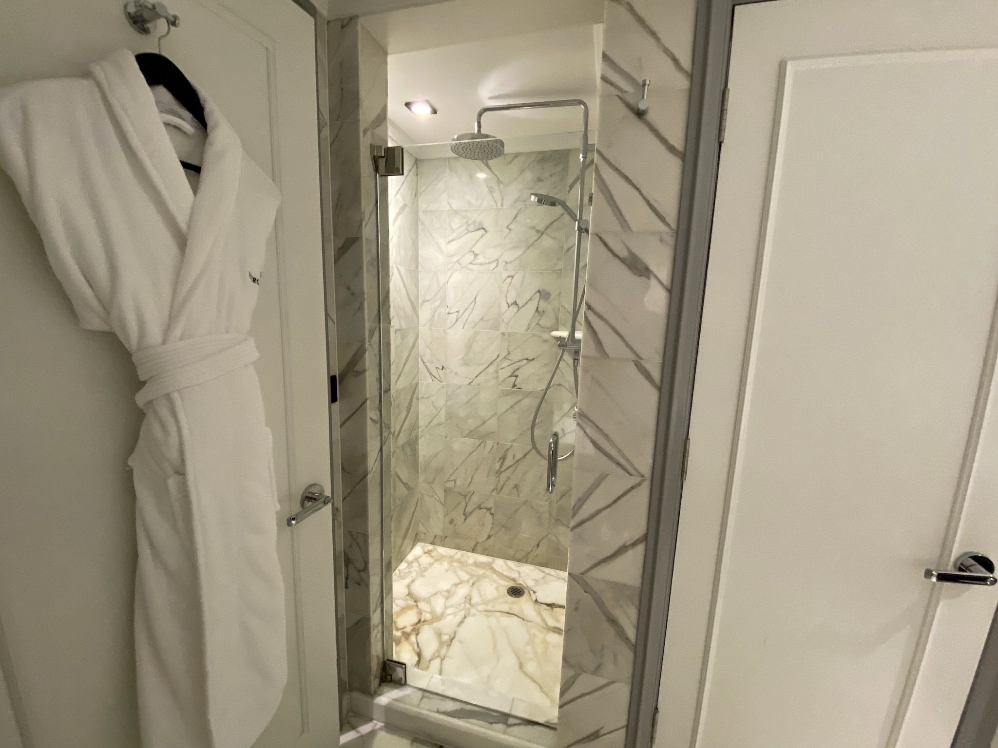 a white bathrobe on a glass shower