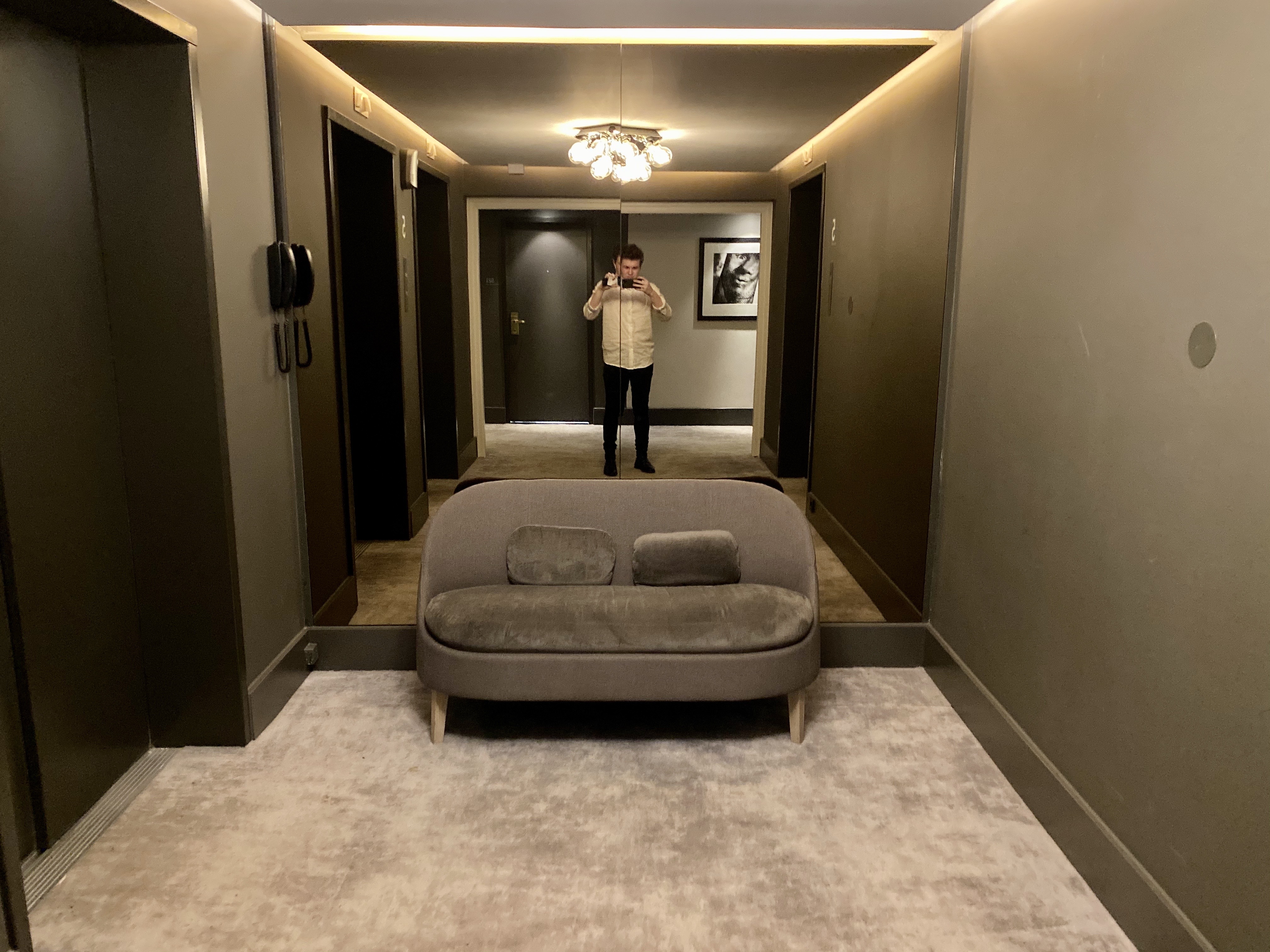 a man taking a picture of a couch in a hallway