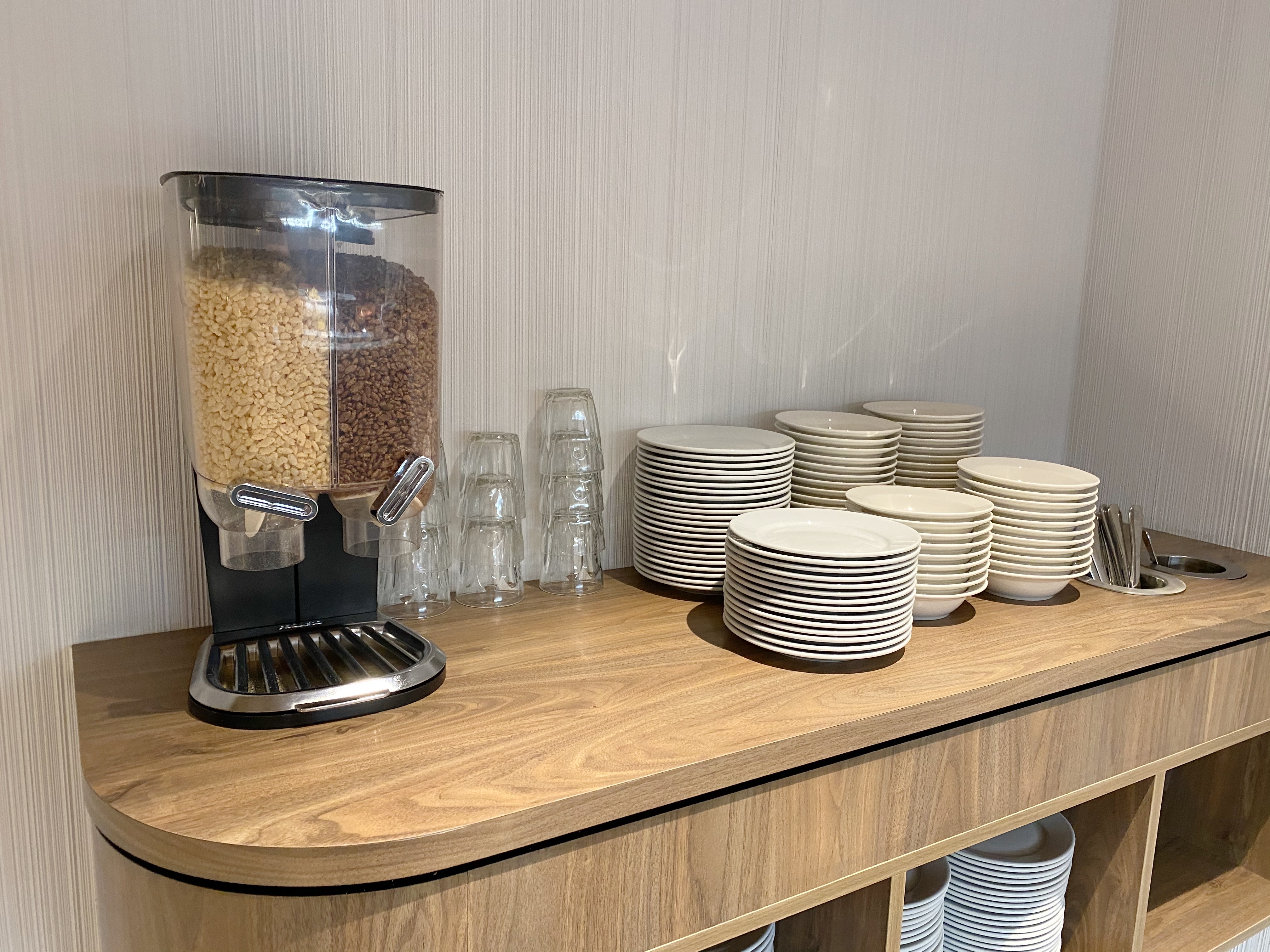 a dispenser with cereals and plates on a counter