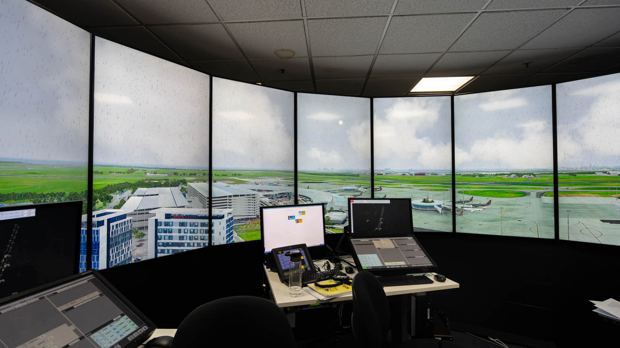 a desk with computers and a large window with a view of an airport