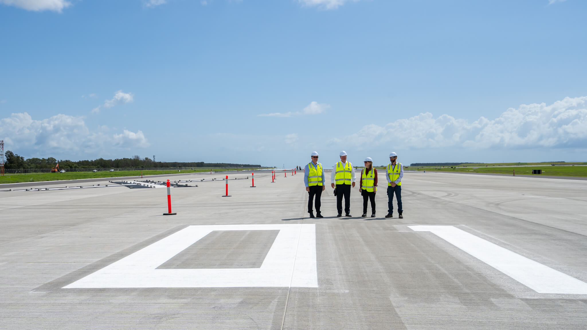 a group of men wearing safety vests and helmets standing on a runway