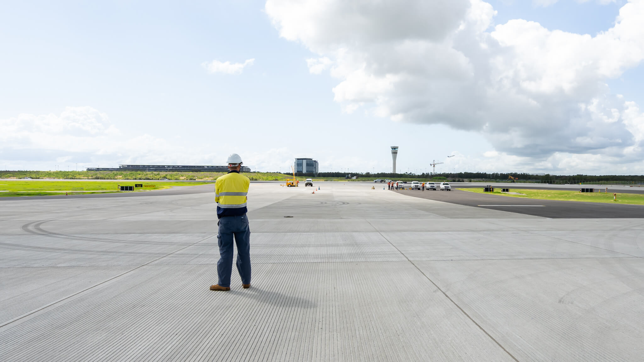 a man in a yellow vest and hardhat standing on a runway